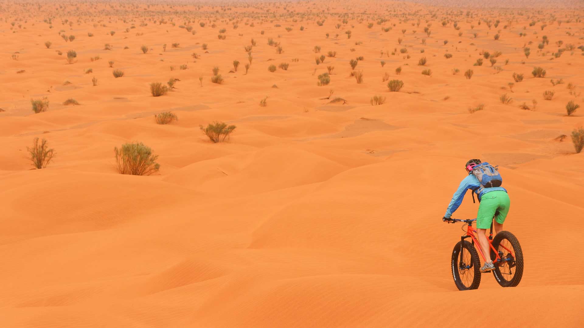 un fat bike part en direction d'une infinité de dunes