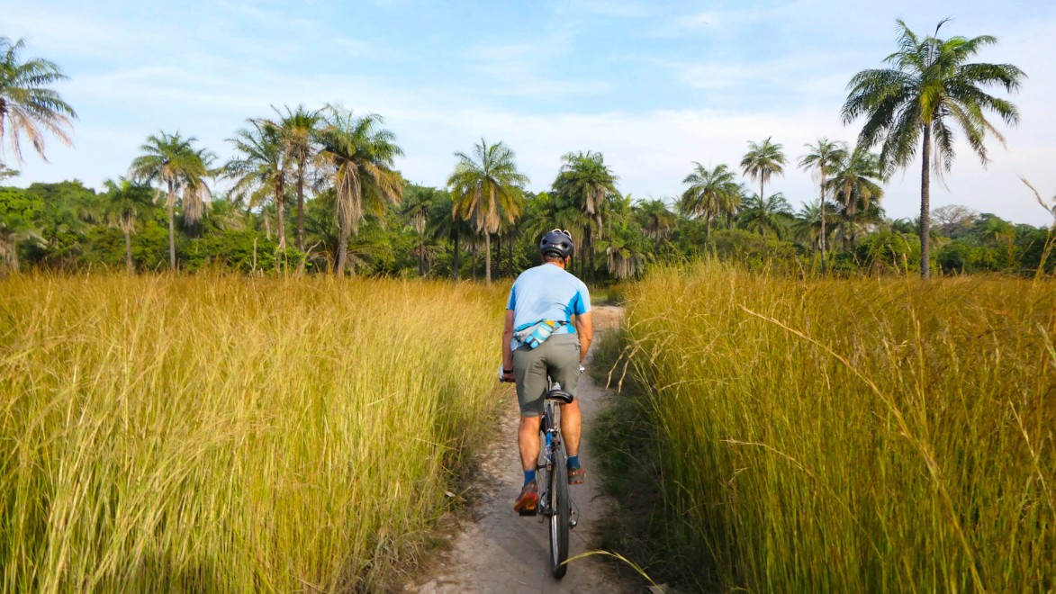 Cycliste sur un petit sentier au cœur de la végétation luxuriante de la Casamance