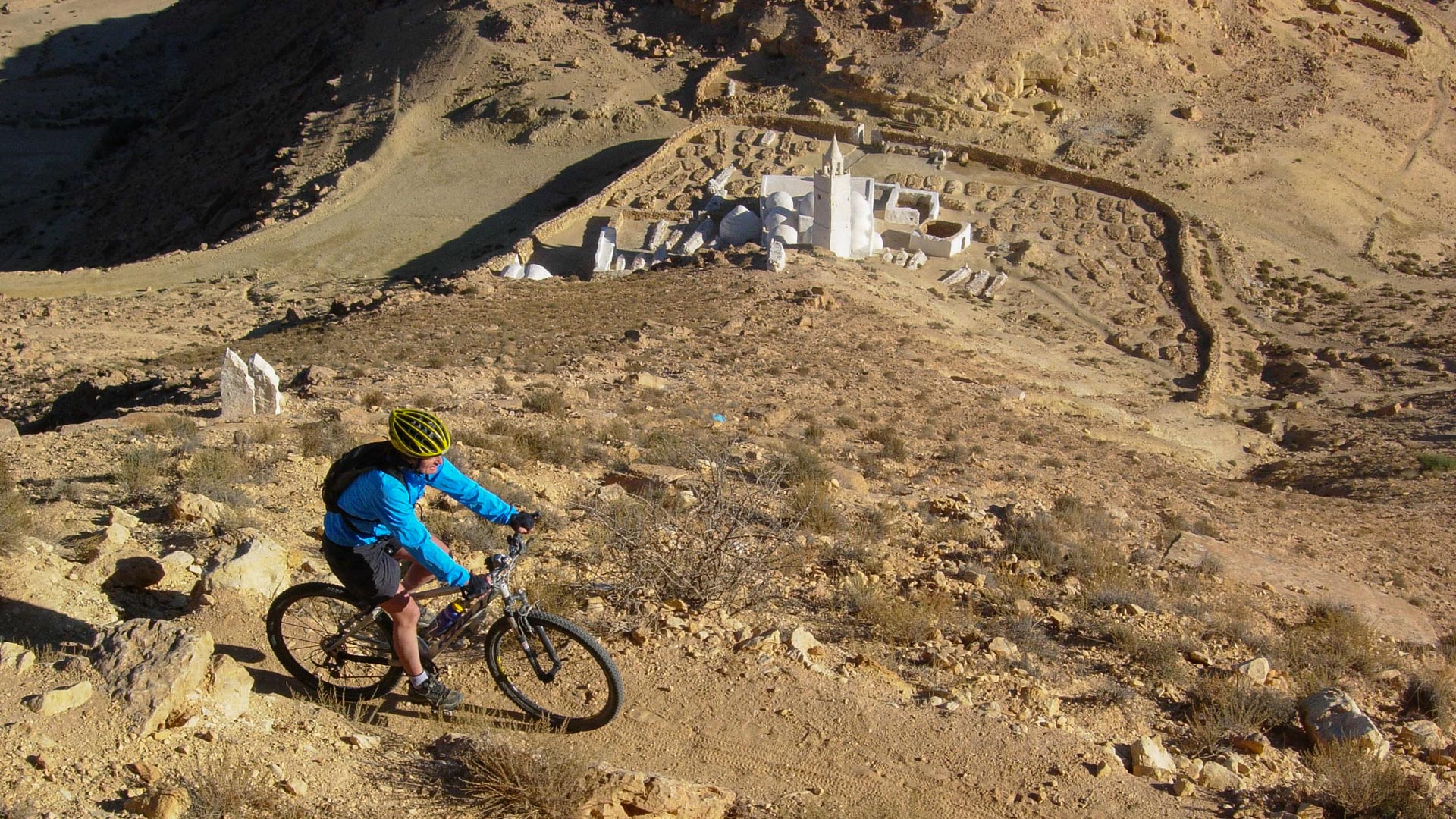 une mosquée apparaît en contre bas d'un single track où roule un VTT