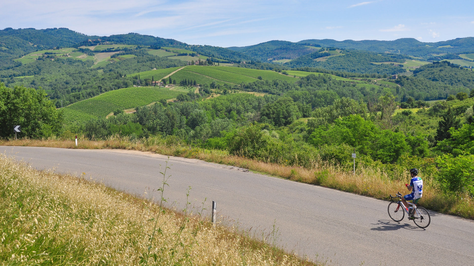 cycliste sur une route avec la vue sur les collines et les vignobles de Toscane.