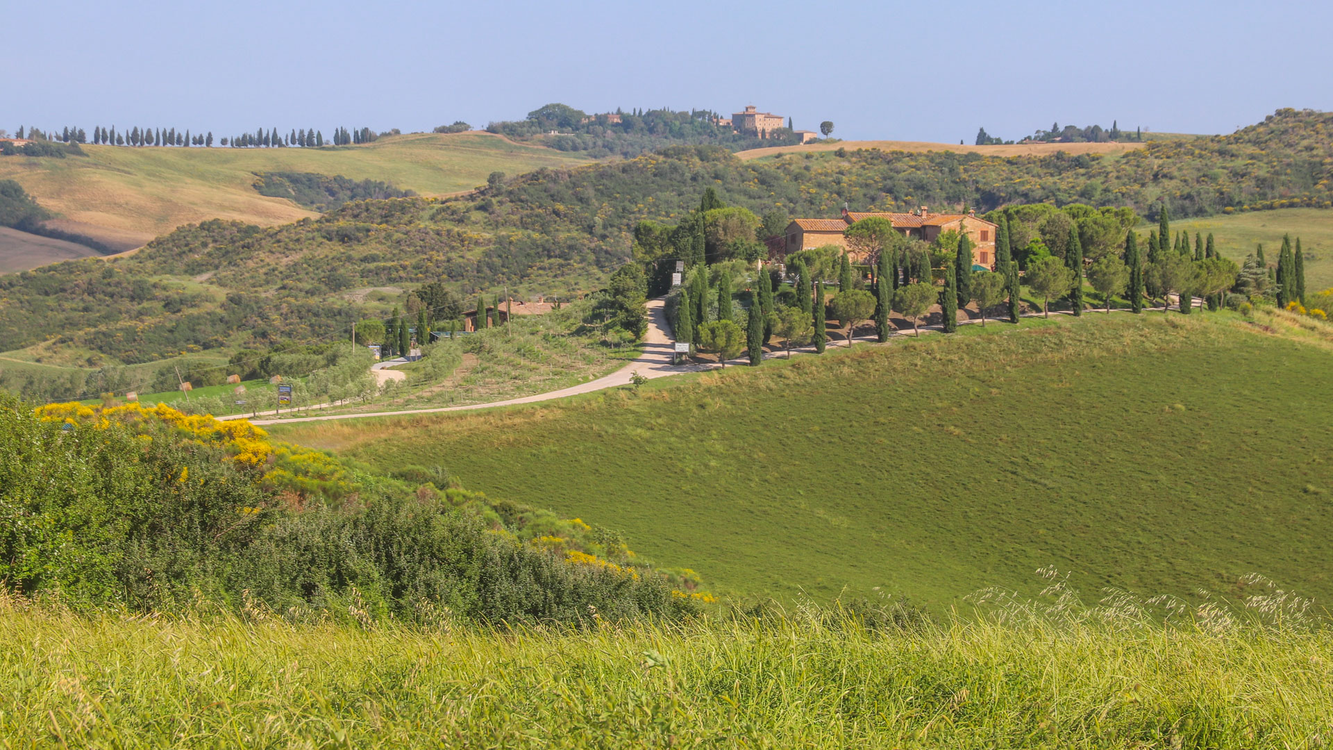 vue panoramique sur le paysage vallonné de la Toscane, avec des champs secs et un village