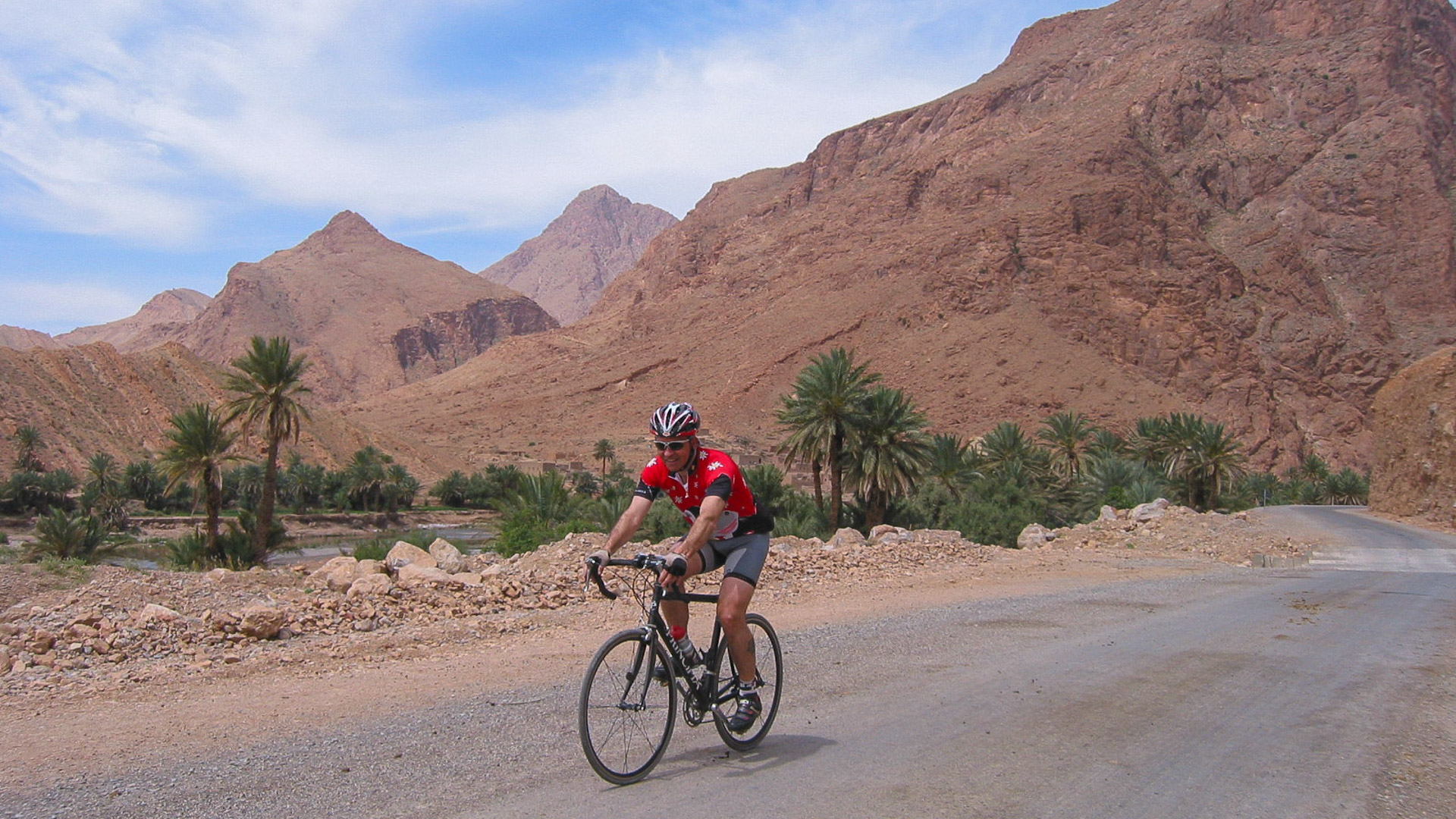 un cycliste sur une route au cœur des montagnes ocres de l'Atlas