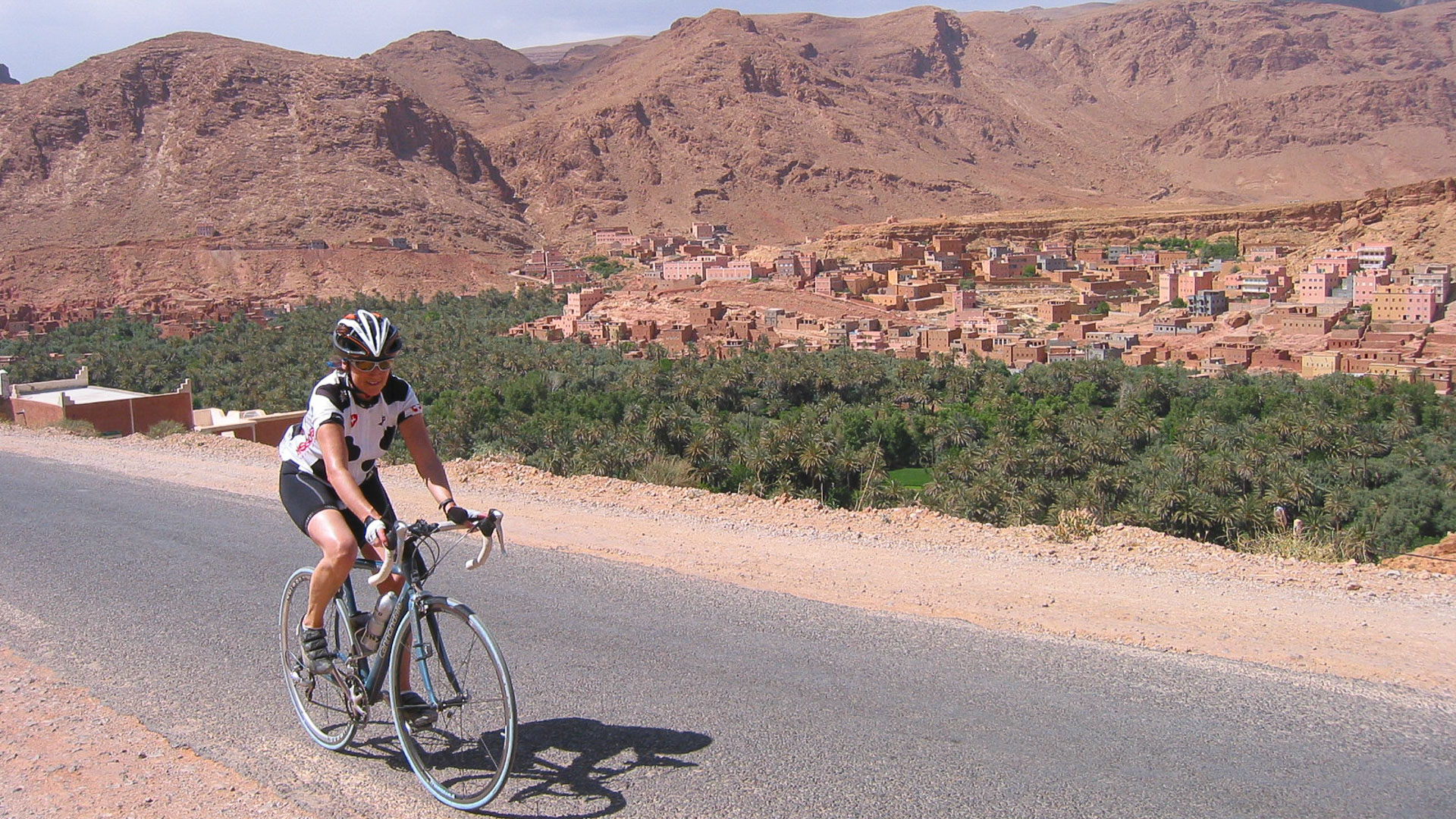 cycliste sur une route qui surplombe un village du Haut-Atlas