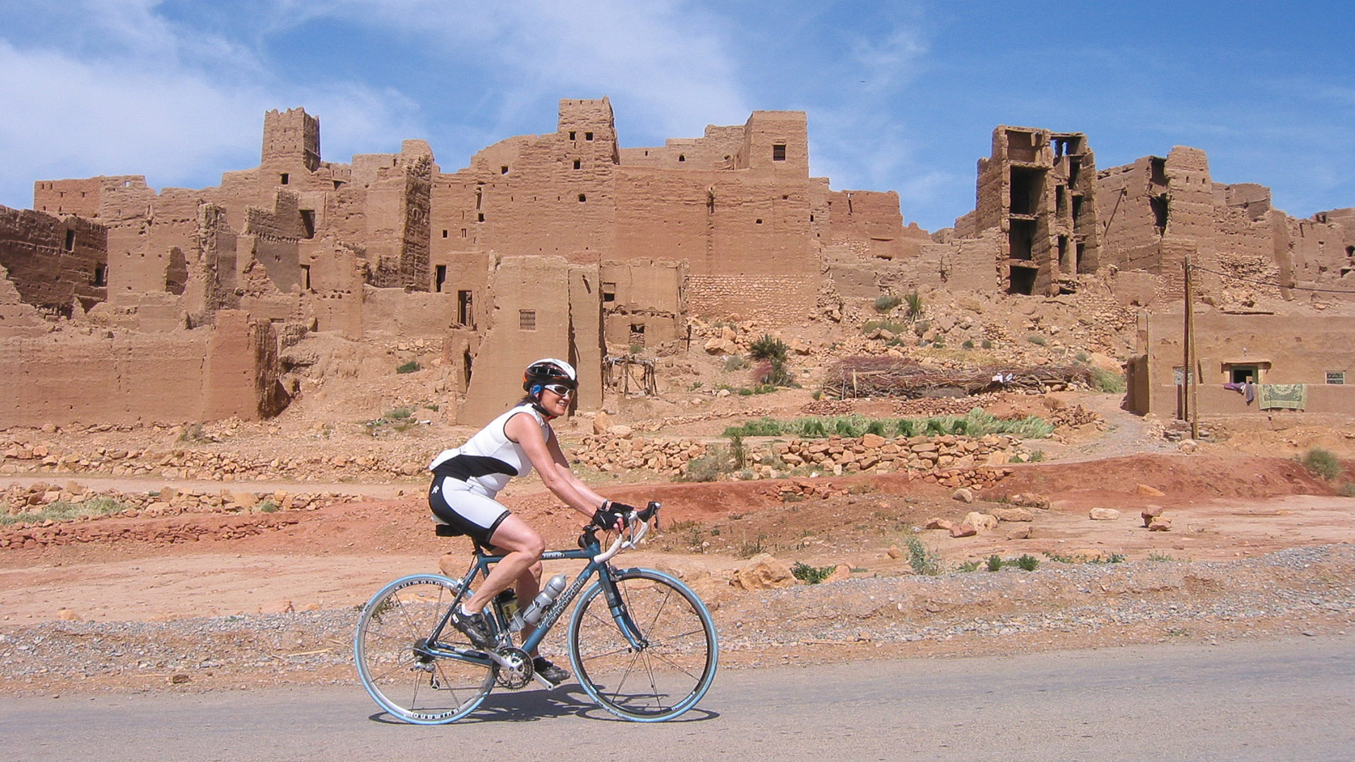 une cycliste qui passe sur une route où se trouve une ancienne cité marocaine