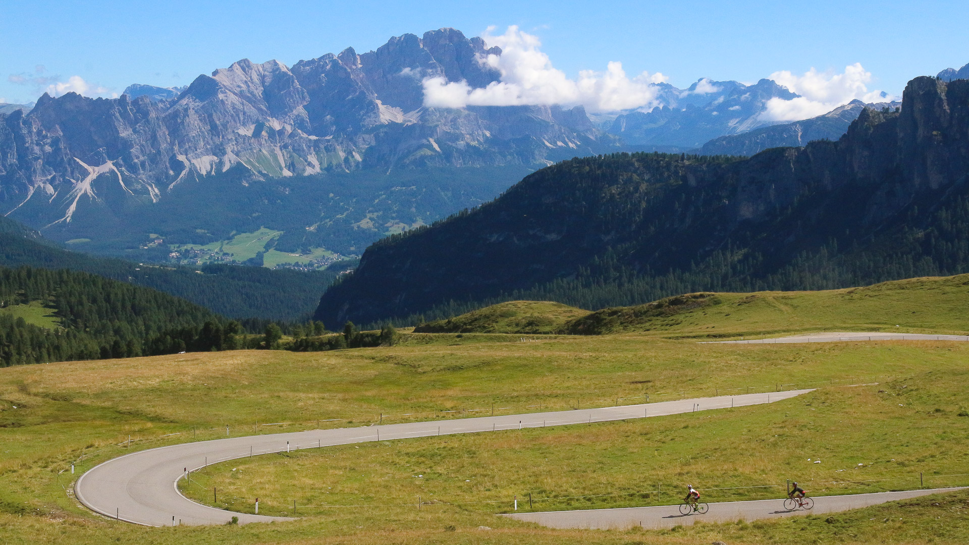 deux cyclistes qui descendent un col dans les Dolomites, avec la vue sur une chaîne de montagne