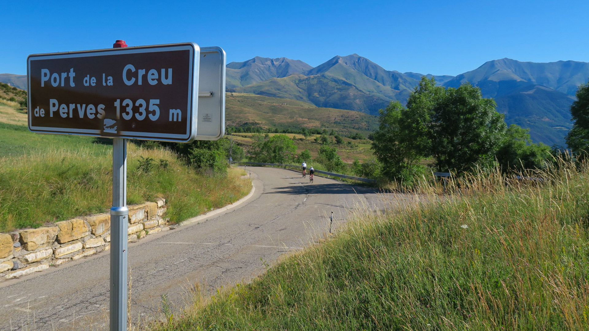 deux cyclistes qui viennent de franchir le Col de la Creu de Pervés 1335m, comme indiqué sur le panneau
