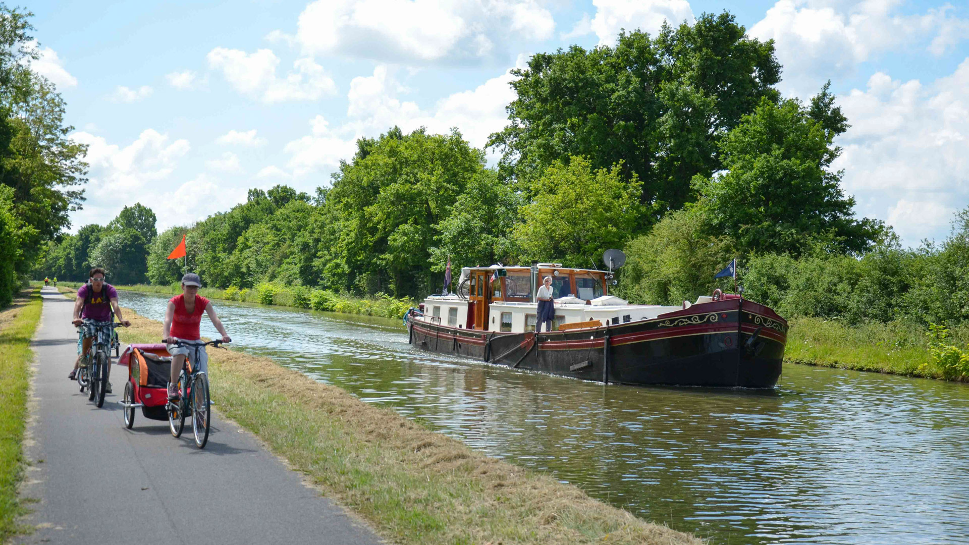 famille à vélo sur le Canal de Bourgogne, devant une péniche