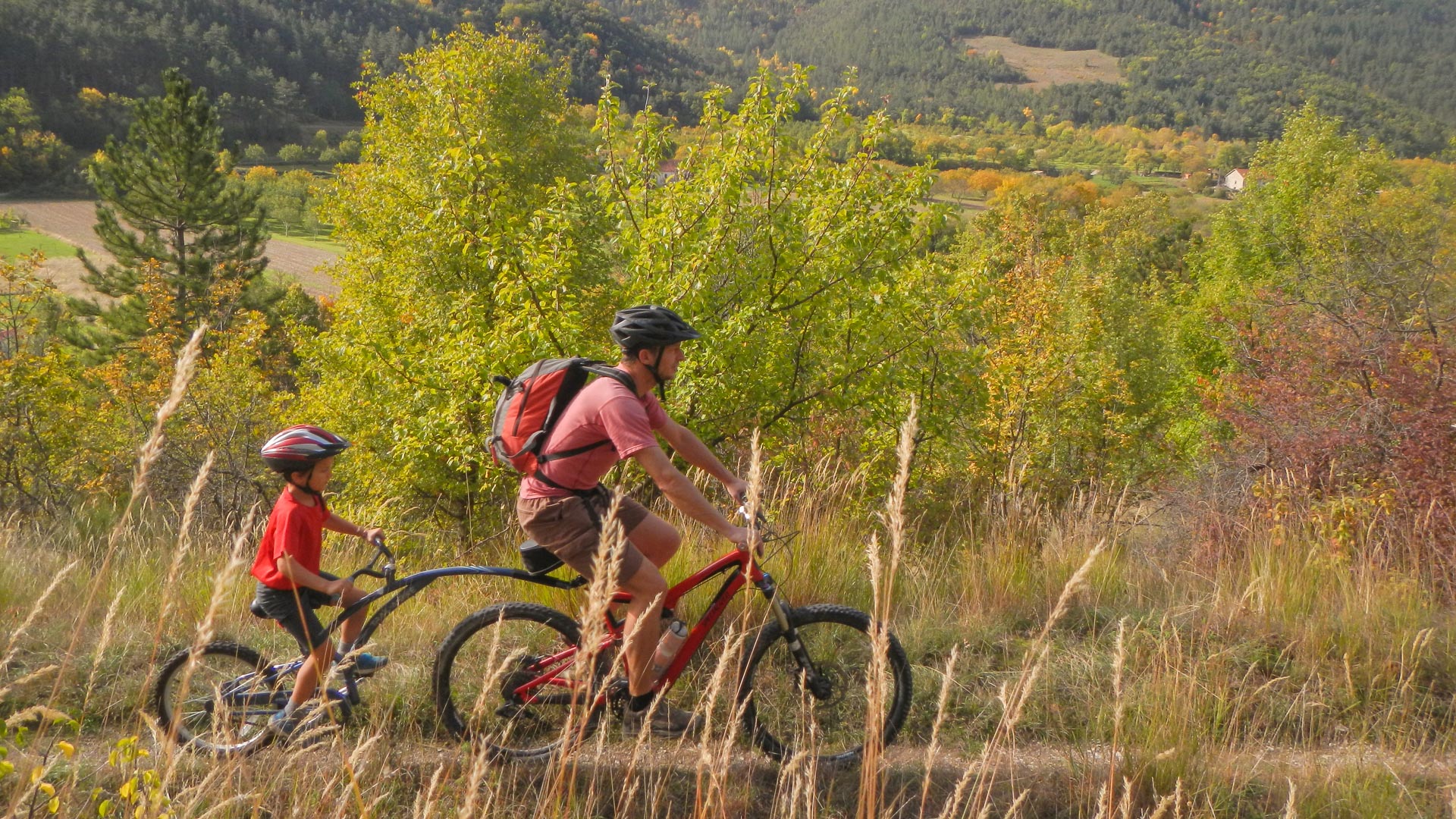 Père et enfant avec un vélo suiveur dans la Drôme