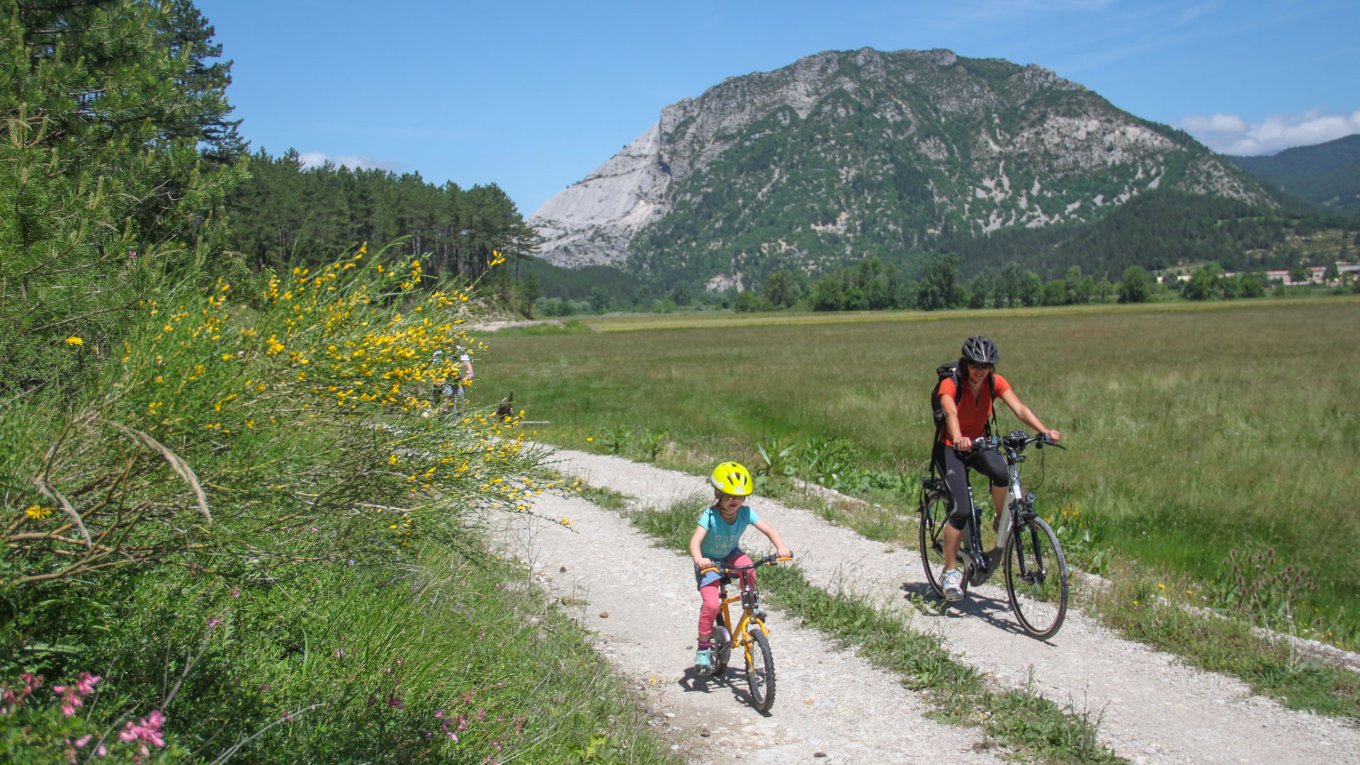 En famille à vélo dans la Drôme, devant la falaise du Claps