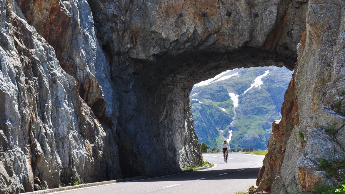 cycliste passe dans un tunnel naturel dans les Alpes Suisses