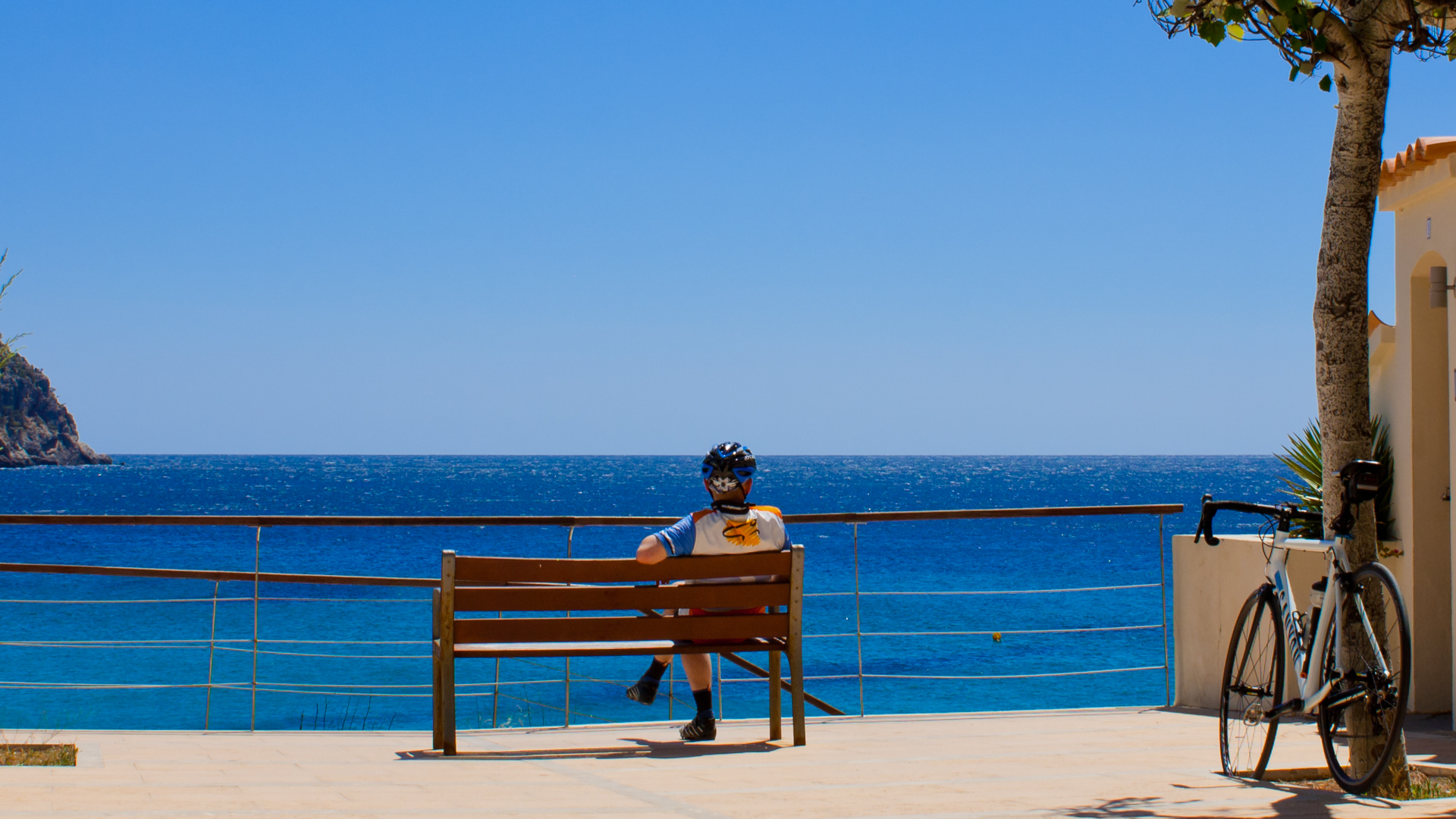 un cycliste qui se repose sur un banc face à la mer Méditerranée