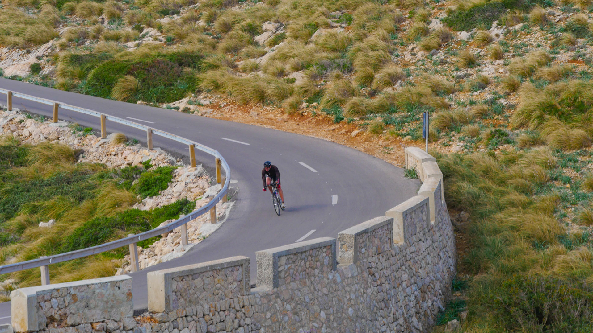 un cycliste en vélo de route qui descend une route en balcon.