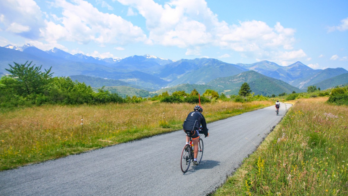 deux cyclistes sur une petite route goudronnée au milieu des champs