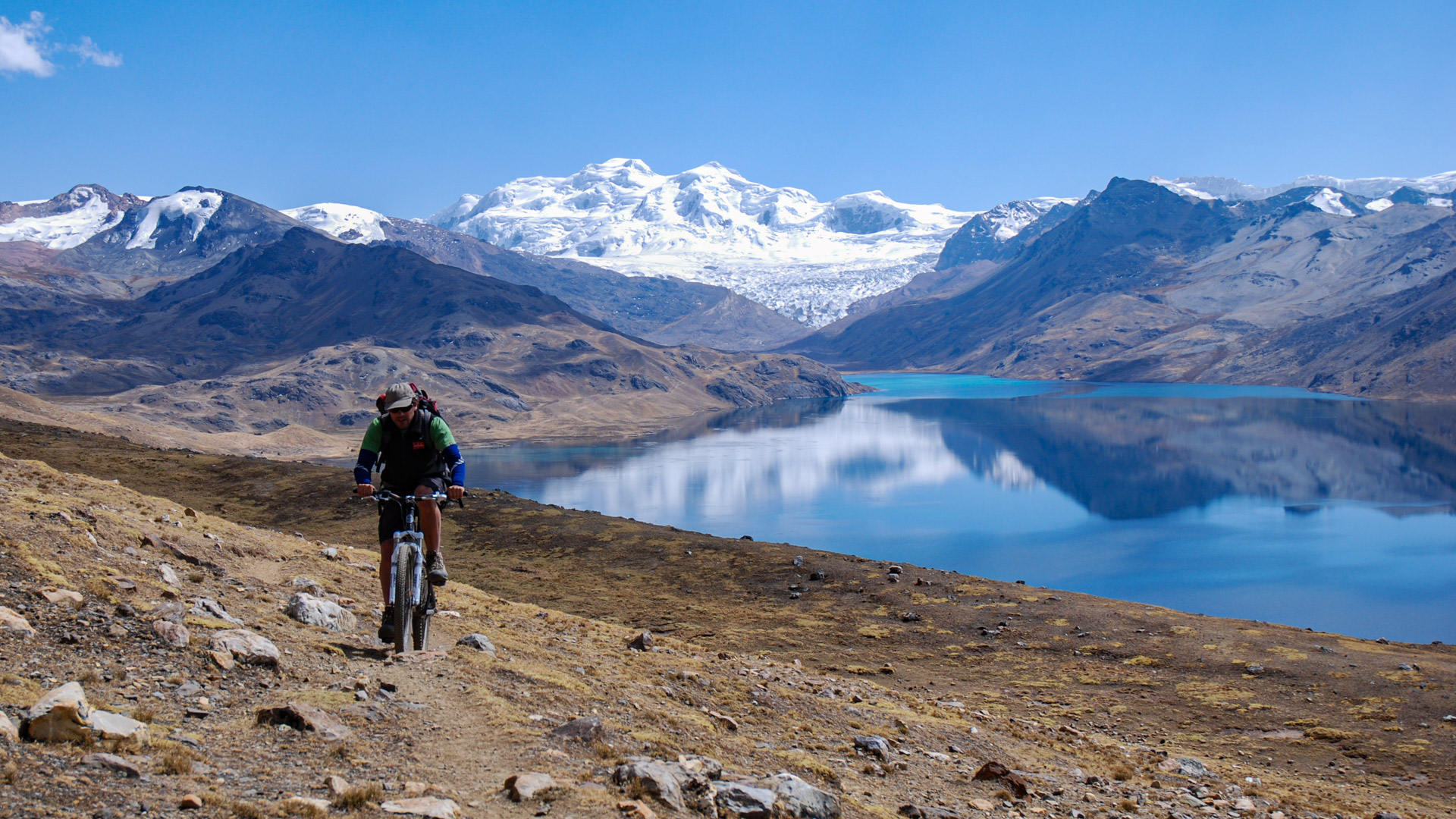 une montagne enneigée se reflète dans un lac sur le tour de l'Ausangate à VTT