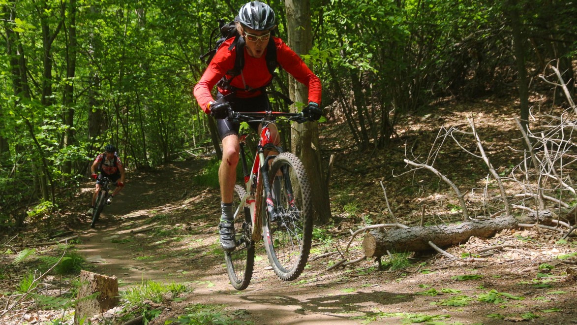 vététiste sur un sentier en forêt réalisant joyeusement un bunny hop