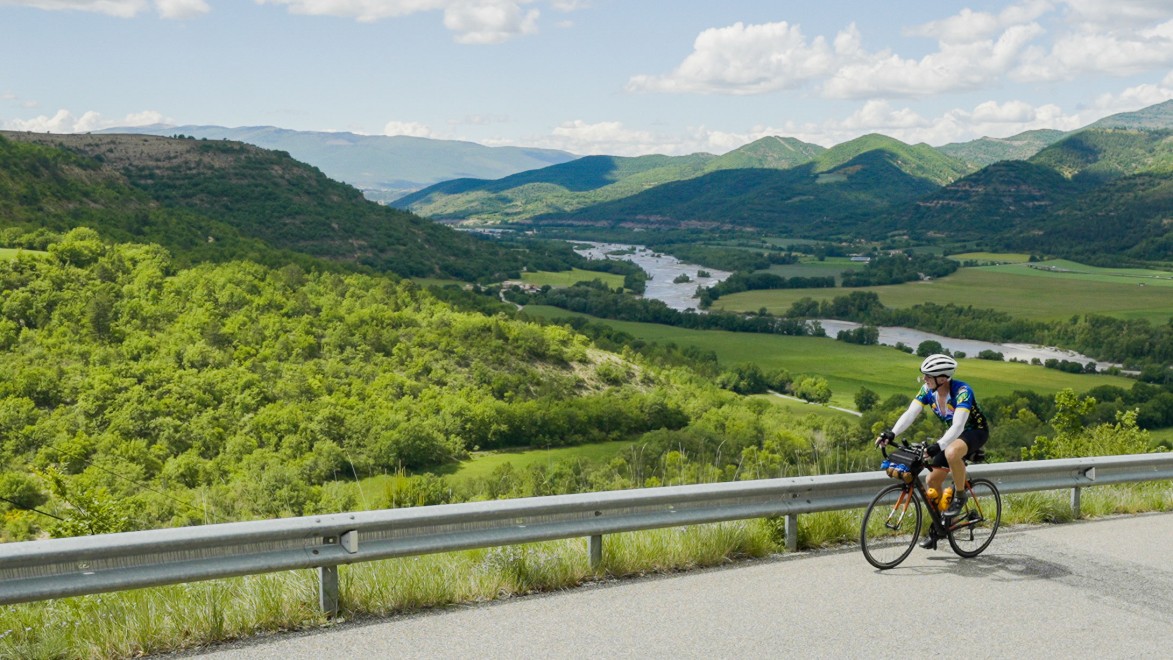 un cycliste sur la montée du col Saint-Jean, avec en arrière plan les moyennes montagnes des Baronnies provençales