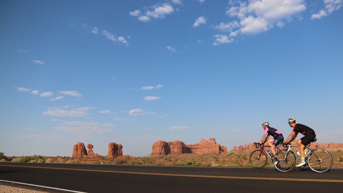 deux cyclistes pris de profil, avec les montagnes ocres de l'ouest américain