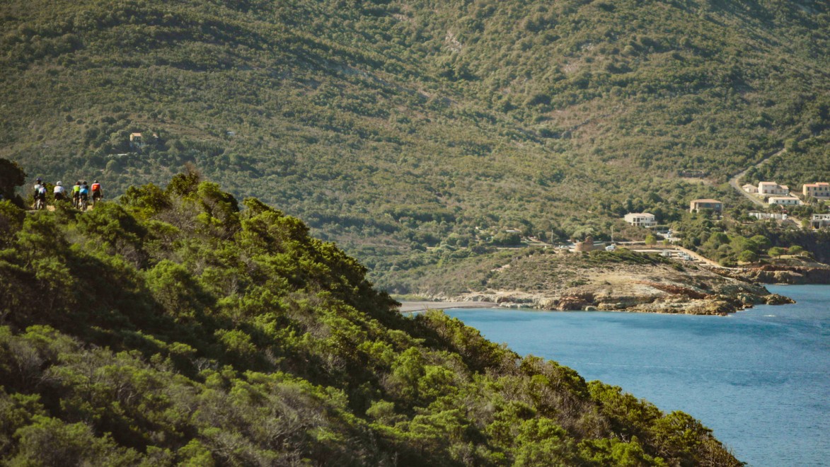 groupe de cyclistes sur une route en balcon surplombant la mer