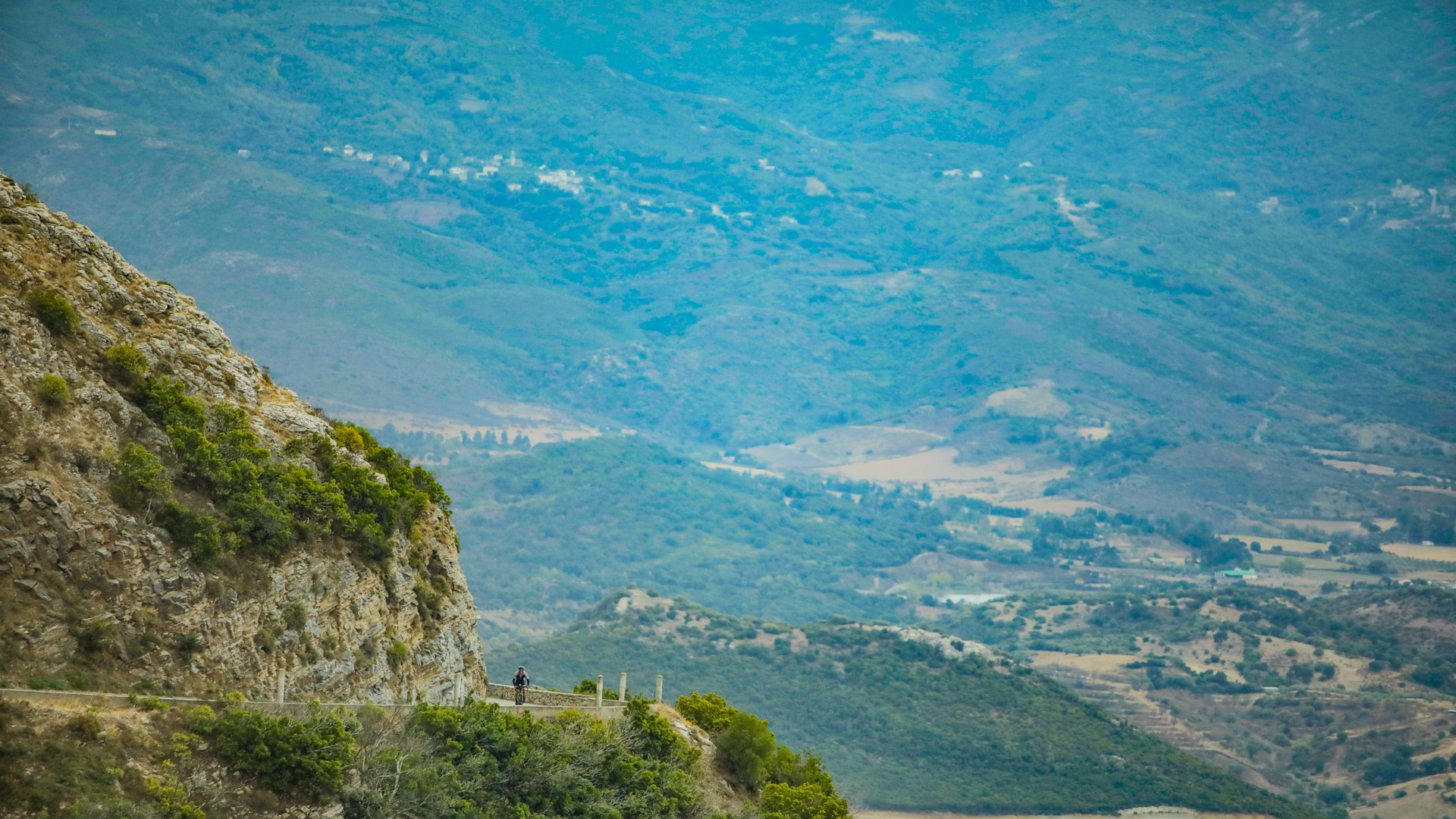 cycliste en train de monter un col sur une route en balcon