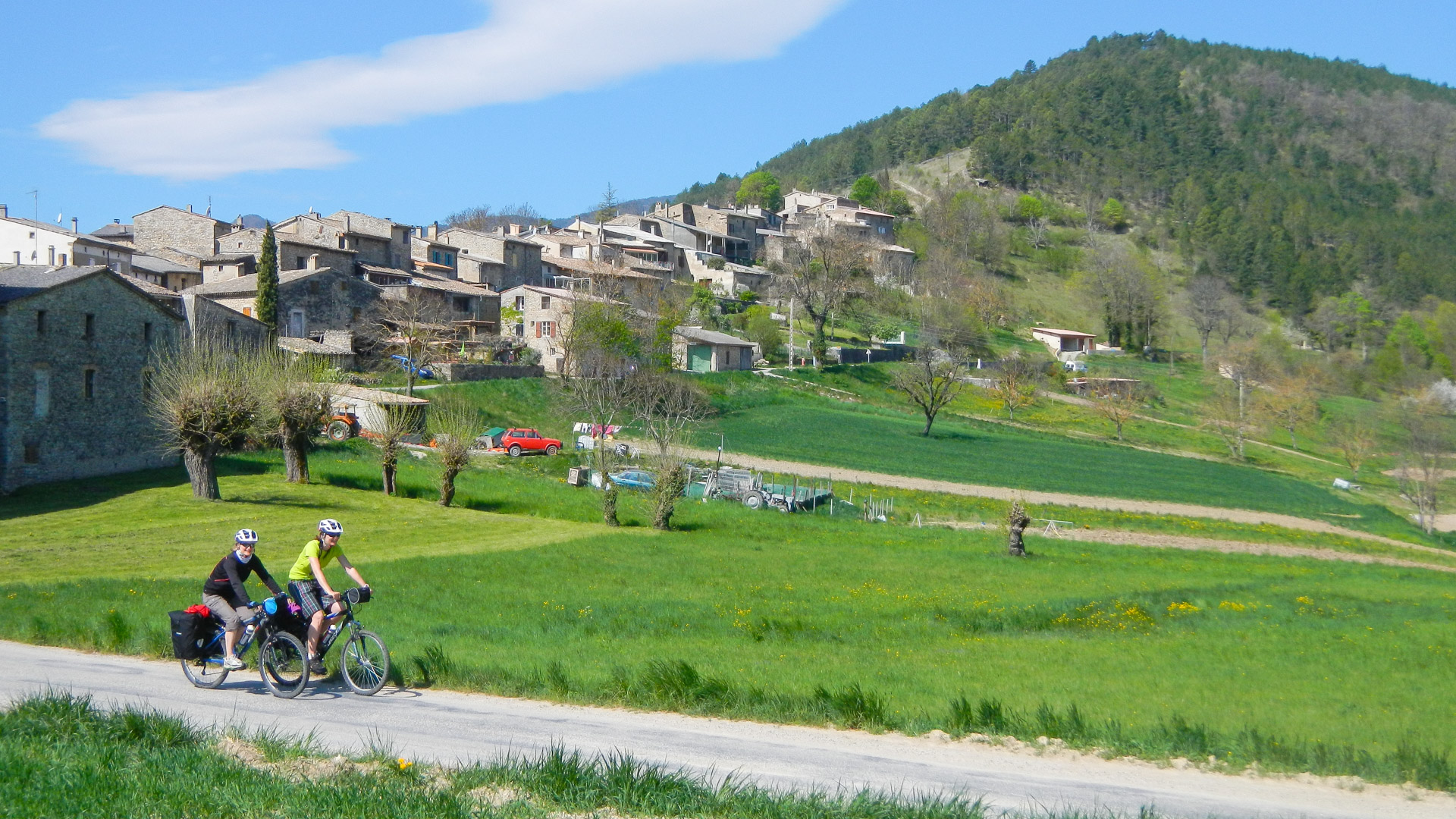 2 cyclistes en vélo-packing, devant un village de la Drôme