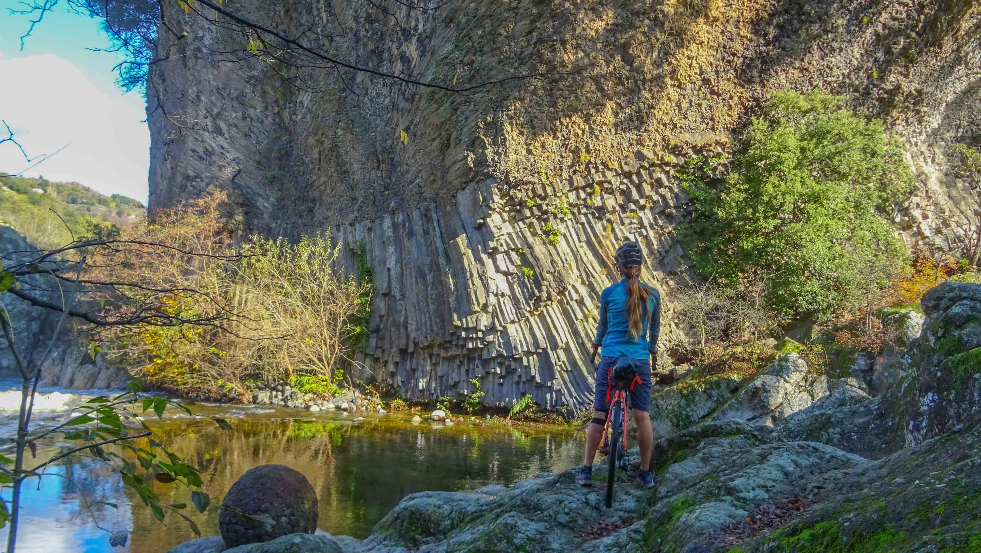 une cycliste devant la coulée basaltique du volcan de Jaujac, en Ardèche
