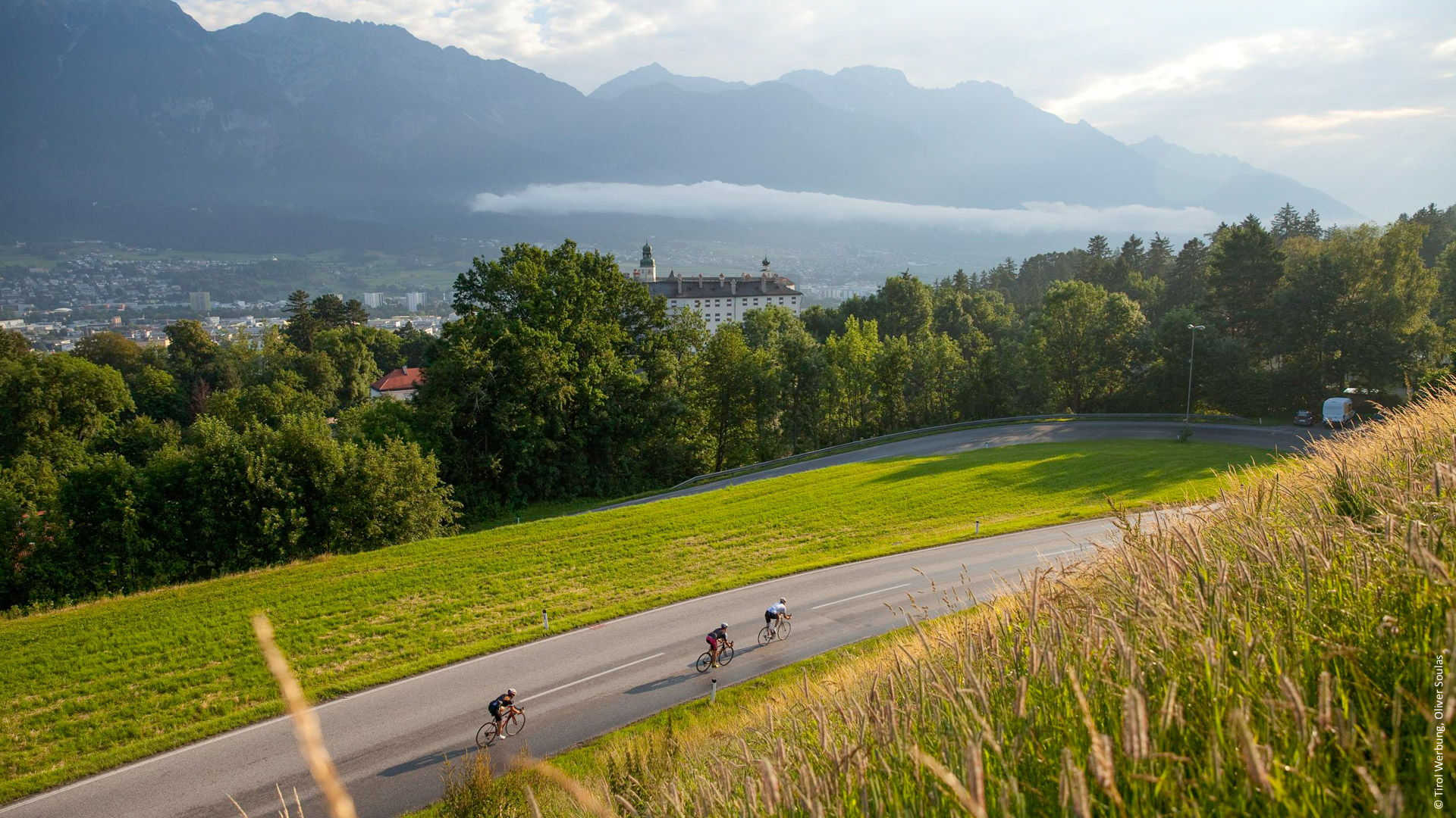 des cyclistes qui descendent les derniers lacets d'un col en direction d'un village autrichien