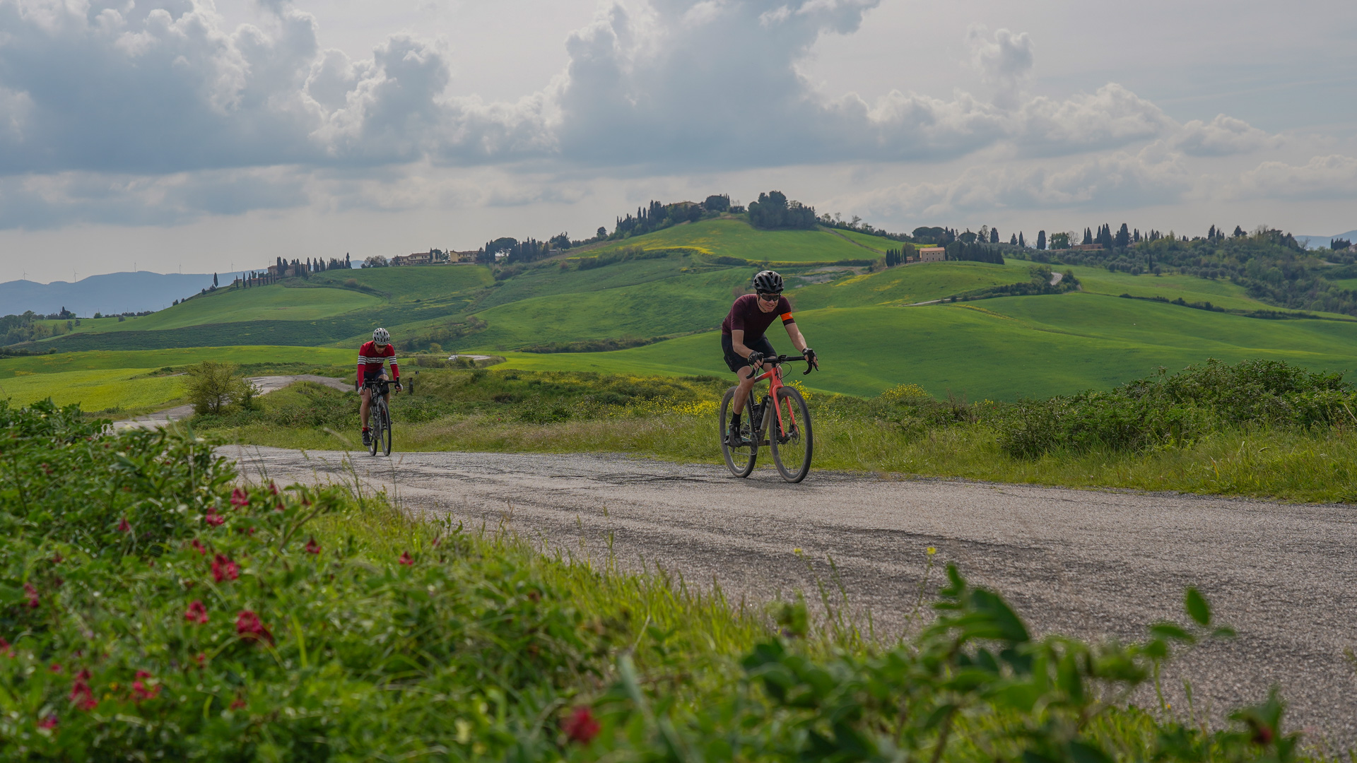 deux cyclistes parcourant une petite route à travers les champs en Toscane