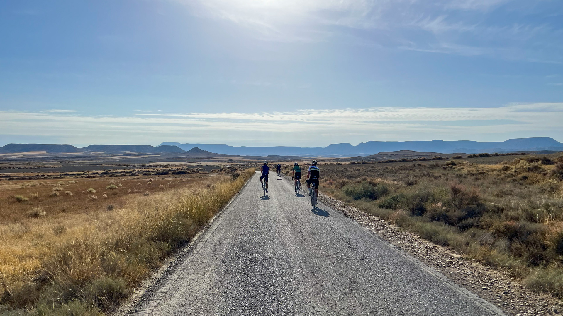 groupe de cyclistes sur une route goudronnée, traversant un plateau en direction du désert