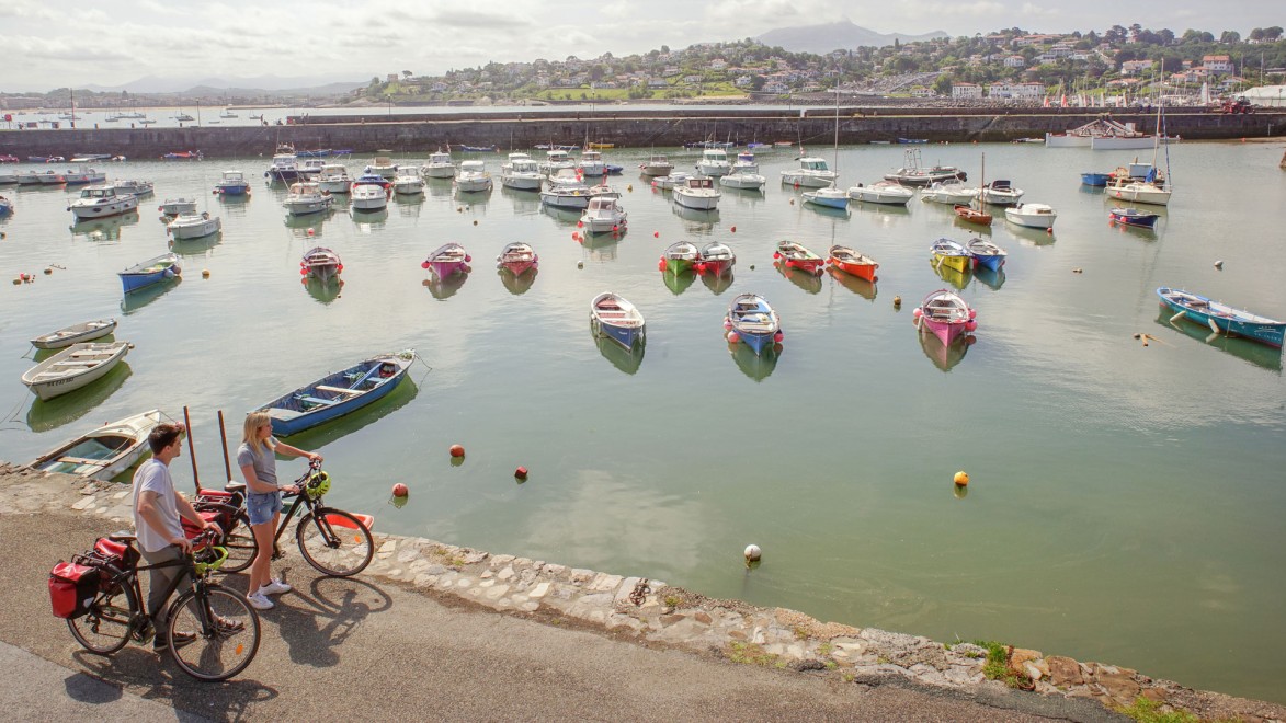 couple de touristes à vélo à côté d'un port du pays basque