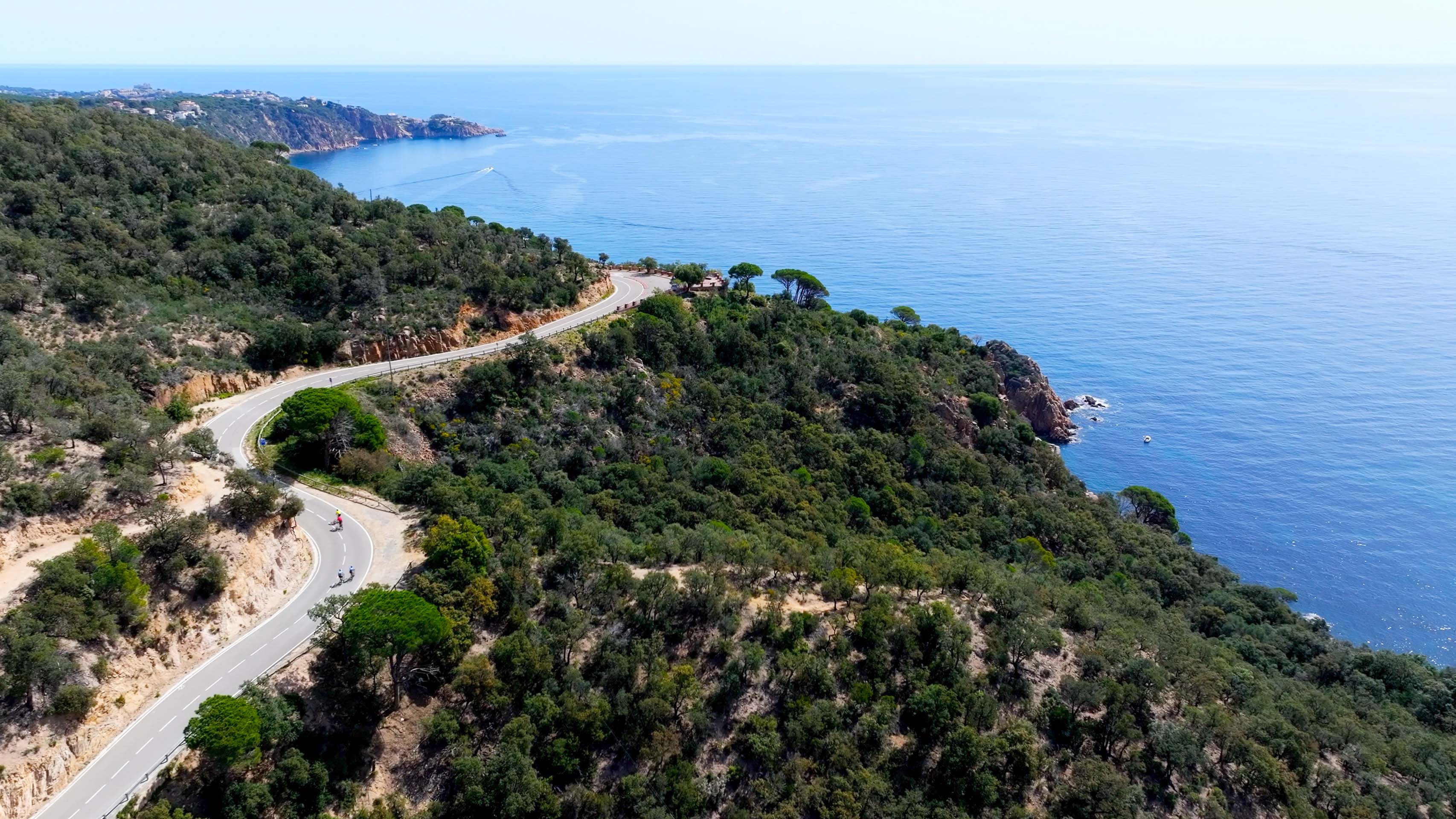 cyclistes sur une route avec une vue en balcon sur la mer.