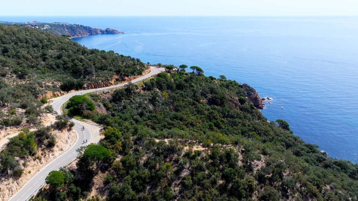 cyclistes sur une route avec une vue en balcon sur la mer.