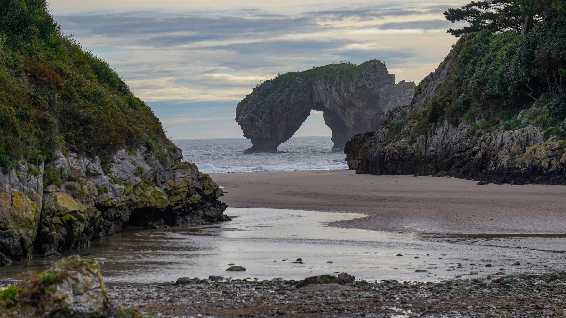 vue sur une arche qui a les pieds dans l'eau depuis une plage de la côte atlantique