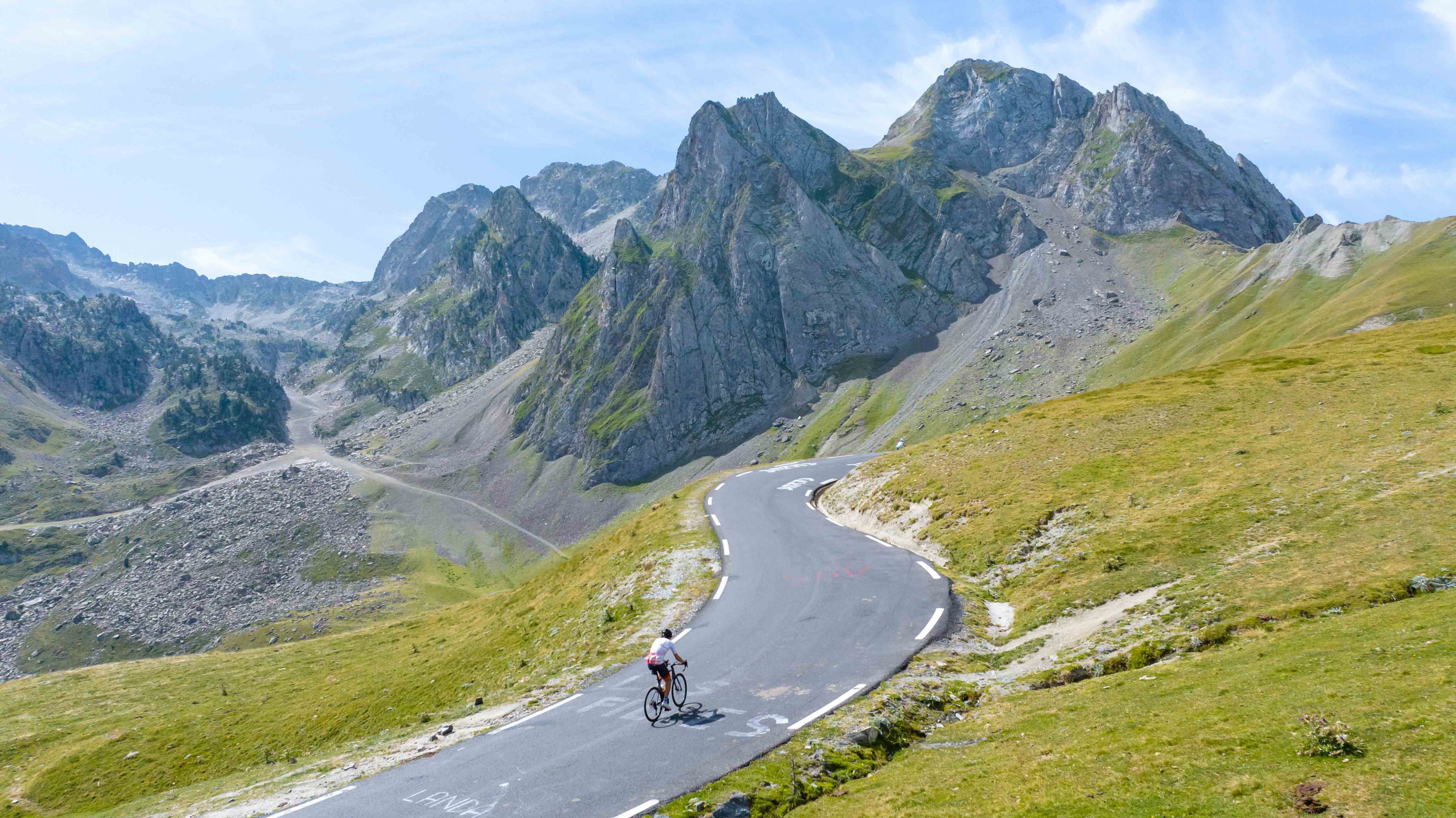 cycliste en pleine ascension du col du Tourmalet, avec le massif montagneux en arrière plan