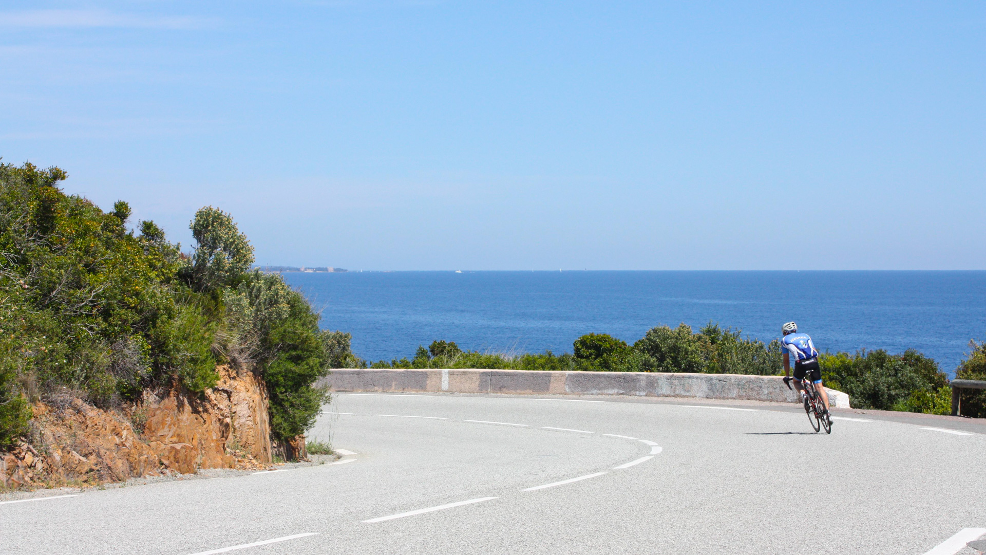 descente d'un cycliste dans un virage avec la mer en arrière-plan