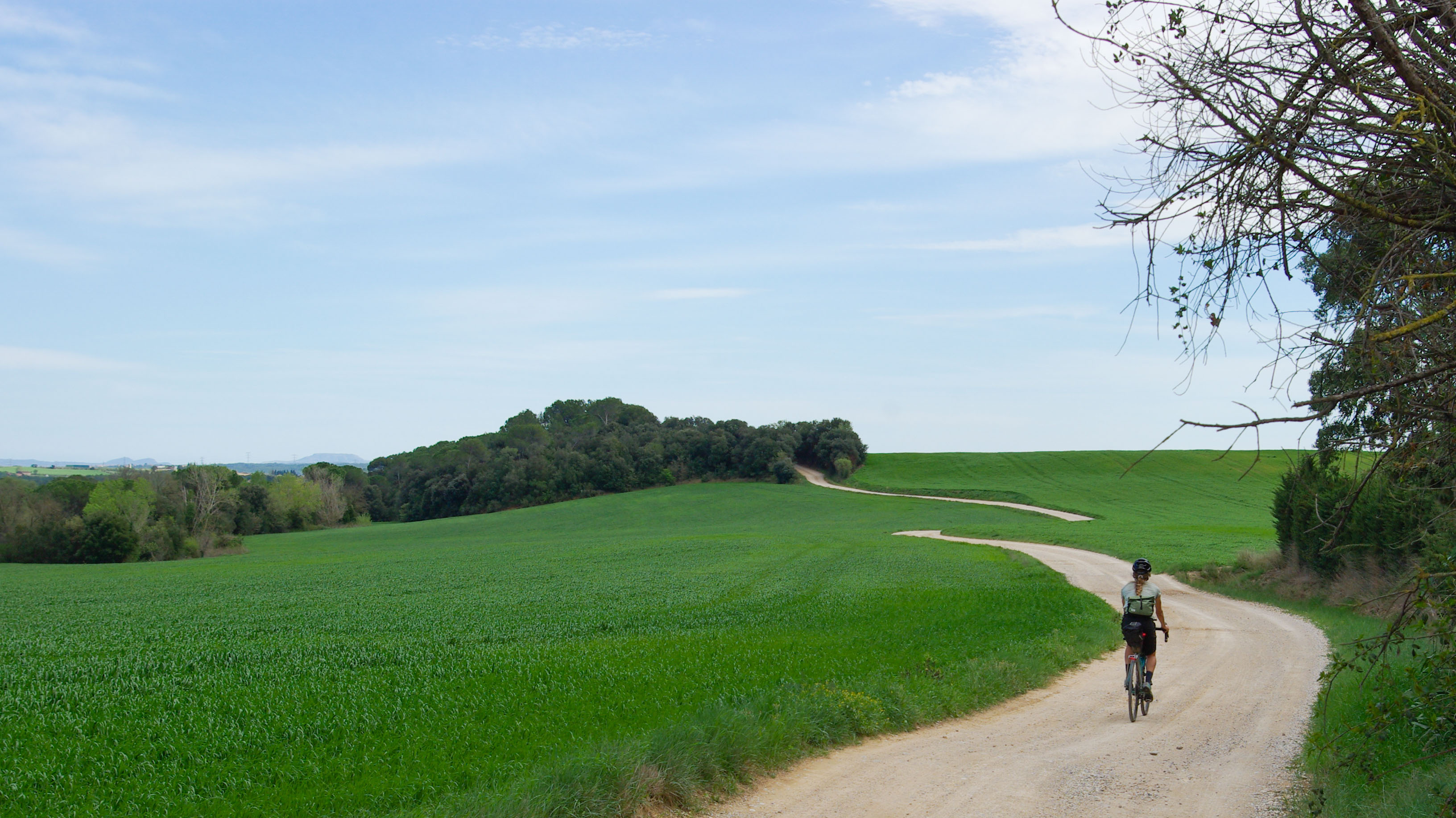 une cycliste de dos sur un petit chemin au milieu d'un plateau dans la Costa Brava