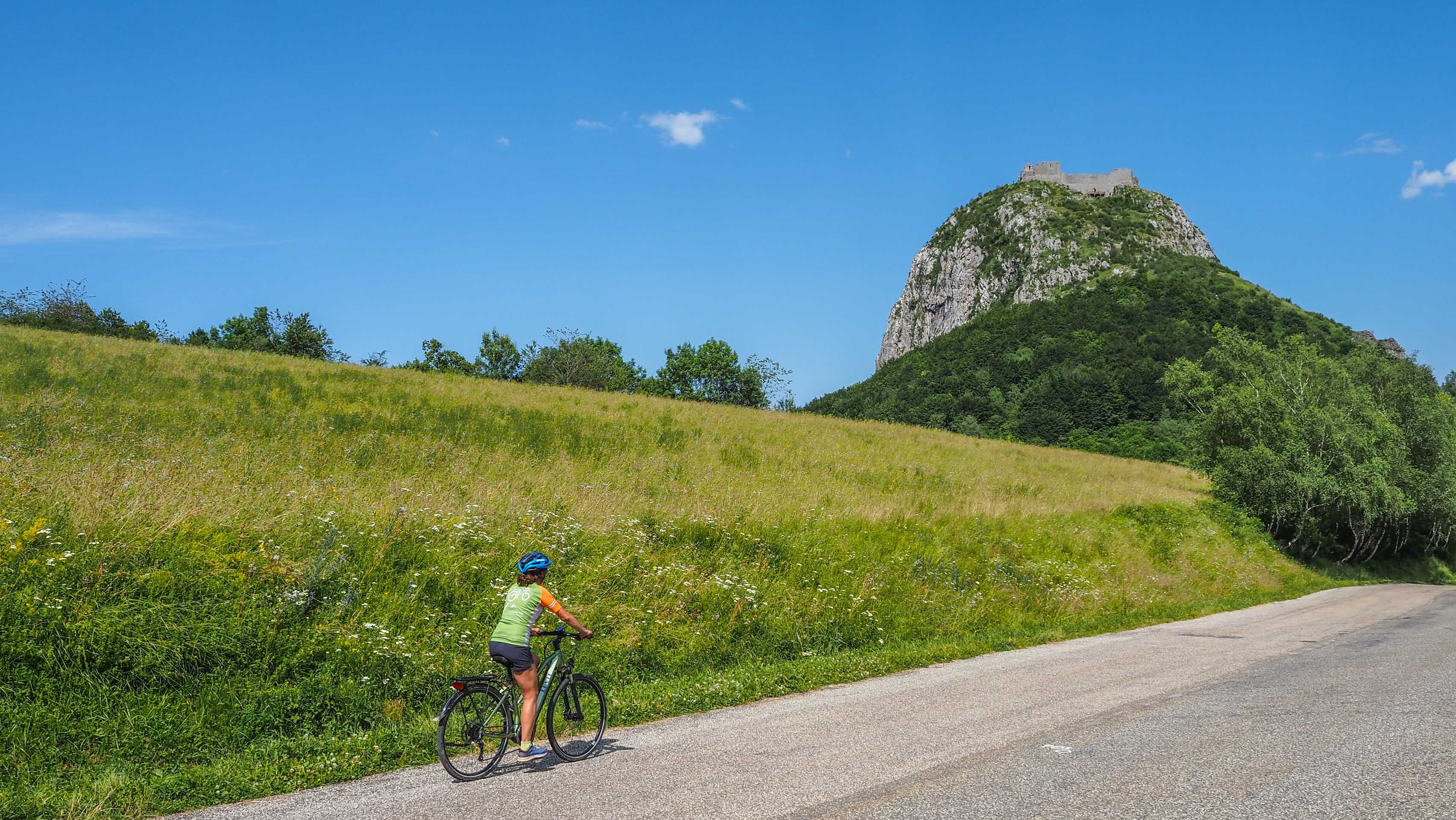 cycliste sur route et château en haut de la colline