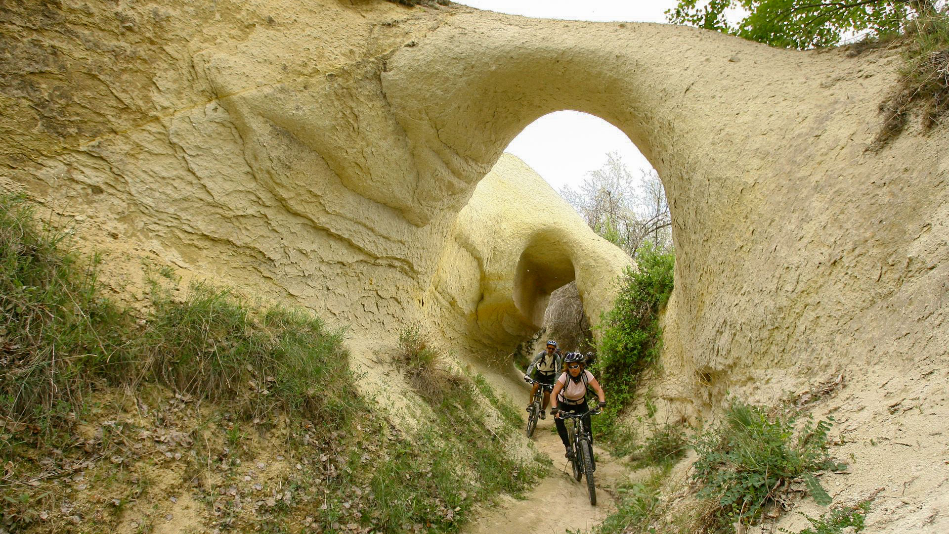 passage sous une arche creusée dans le tuf par l'érosion