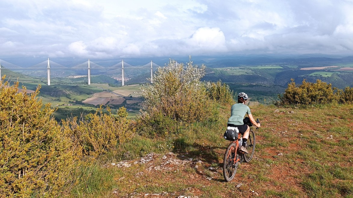 cycliste sur un piste gravel et en arrière-plan le viaduc de Millau