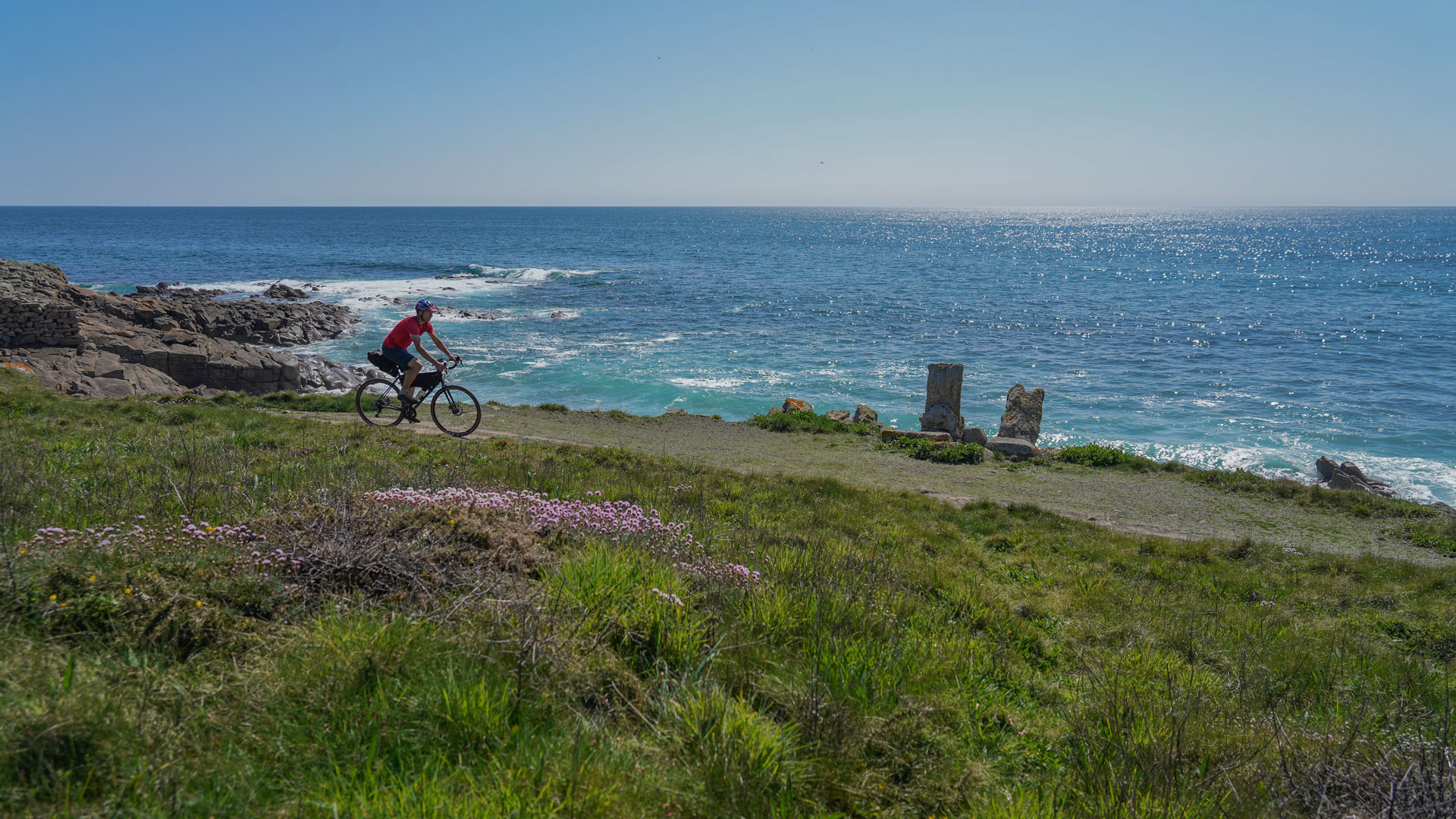 un cycliste roule sur une piste à flanc de falaise
