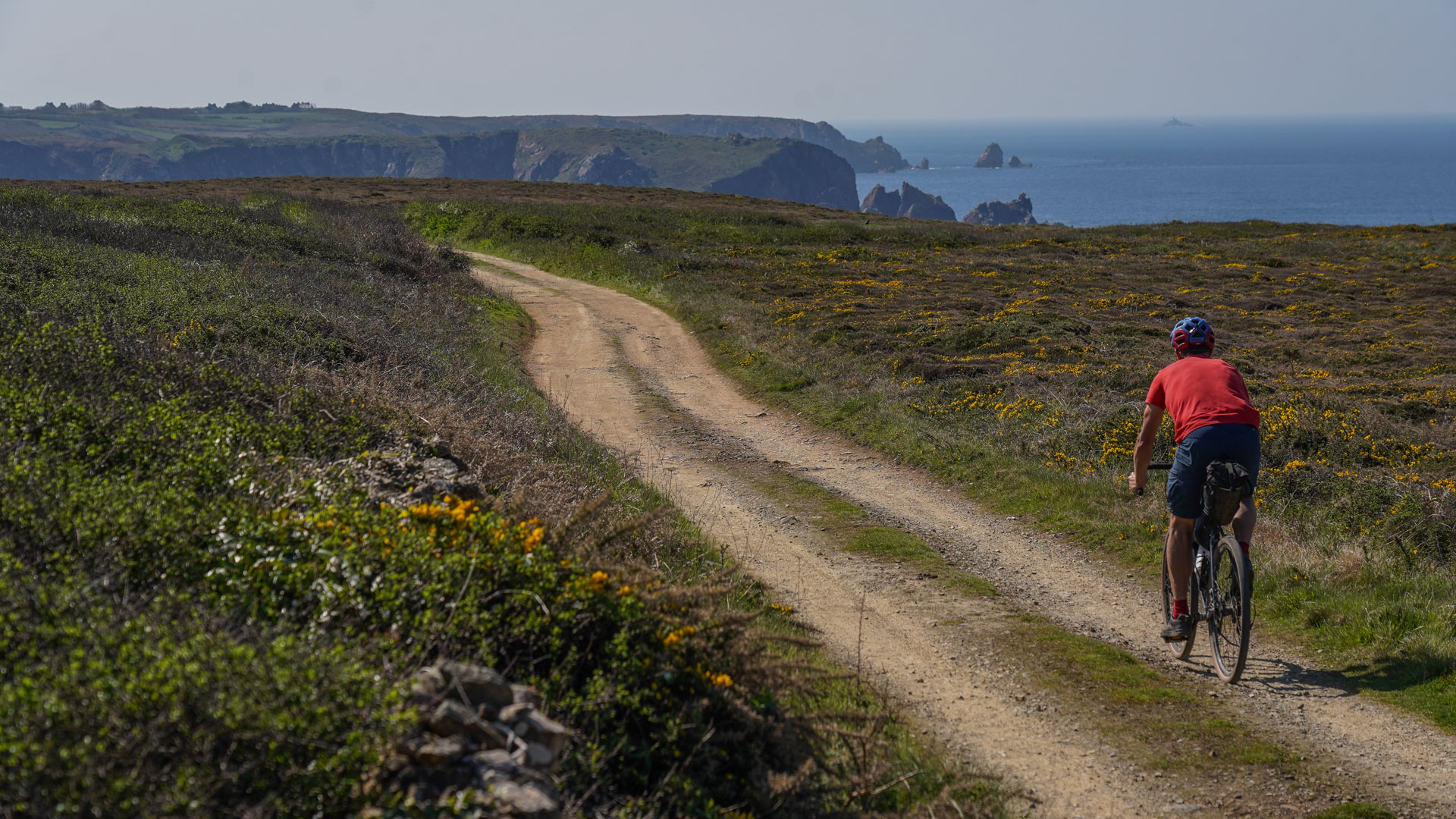 un cycliste roule sur une piste avec des falaises en fond