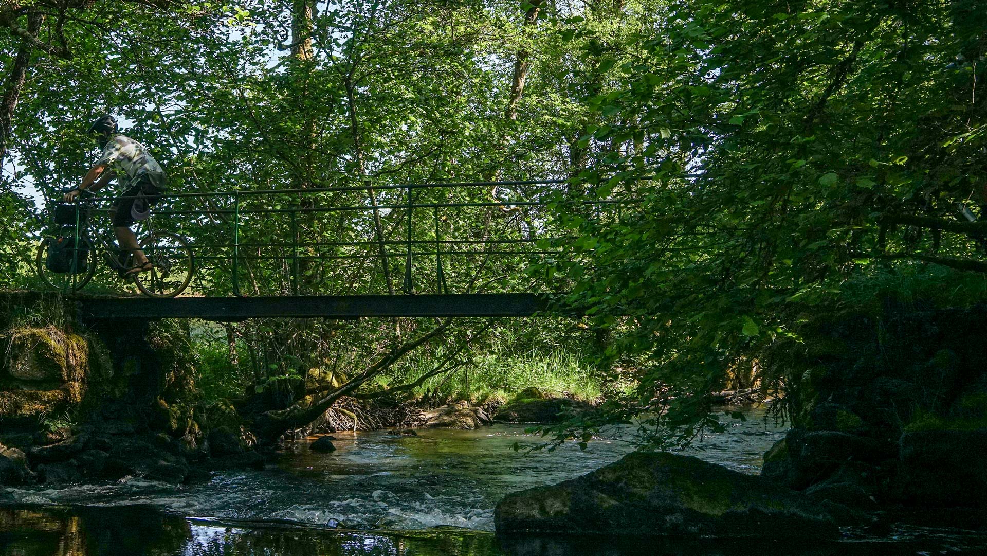 homme à vélo sur une passerelle au dessus de la rivière