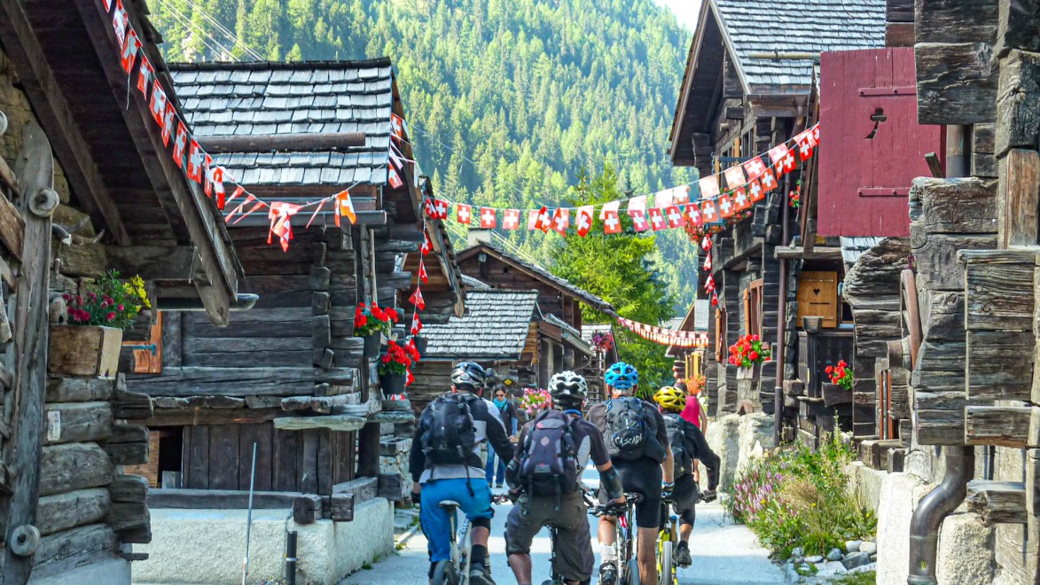 groupe de vététistes traversent le village d'altitude de Grimentz au cœur des Alpes valaisannes.