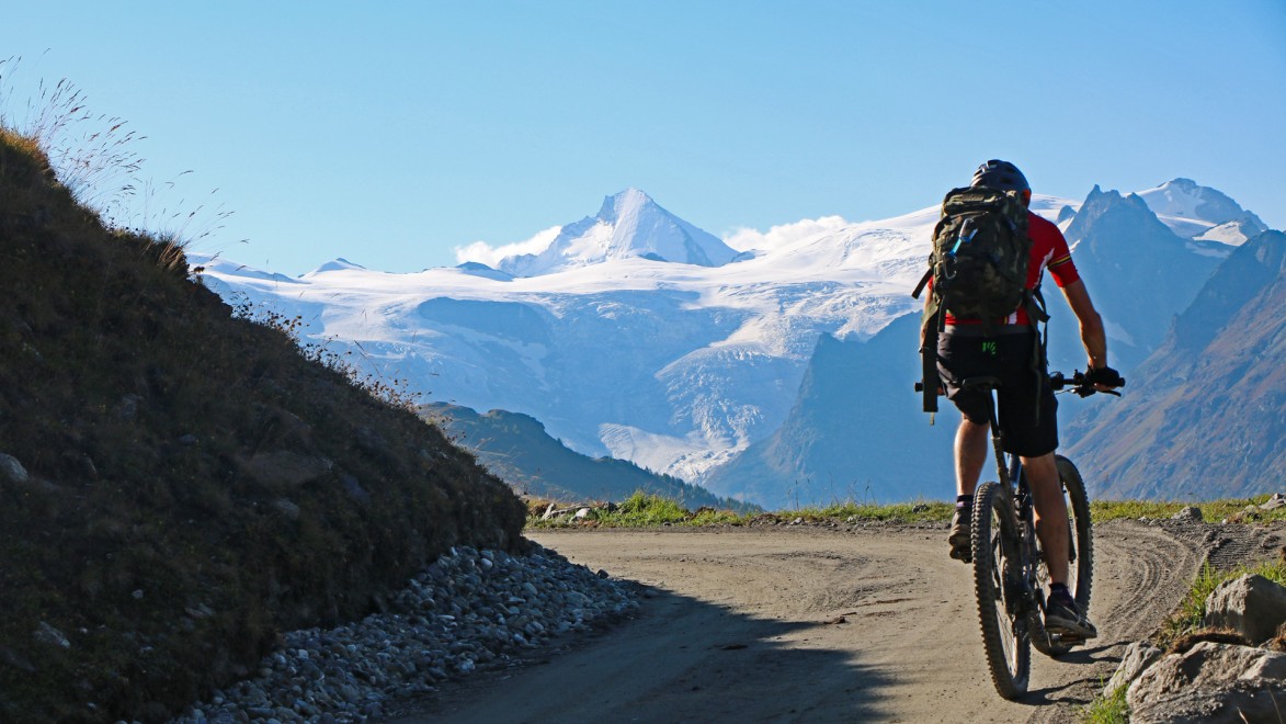 vététiste de dos sur une piste de montagne face à un glacier des alpes suisses