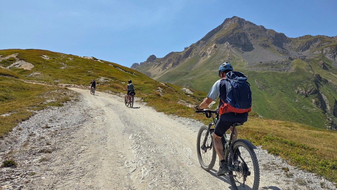 3 vététistes font l'ascension d'une piste de montagne dans les Alpes