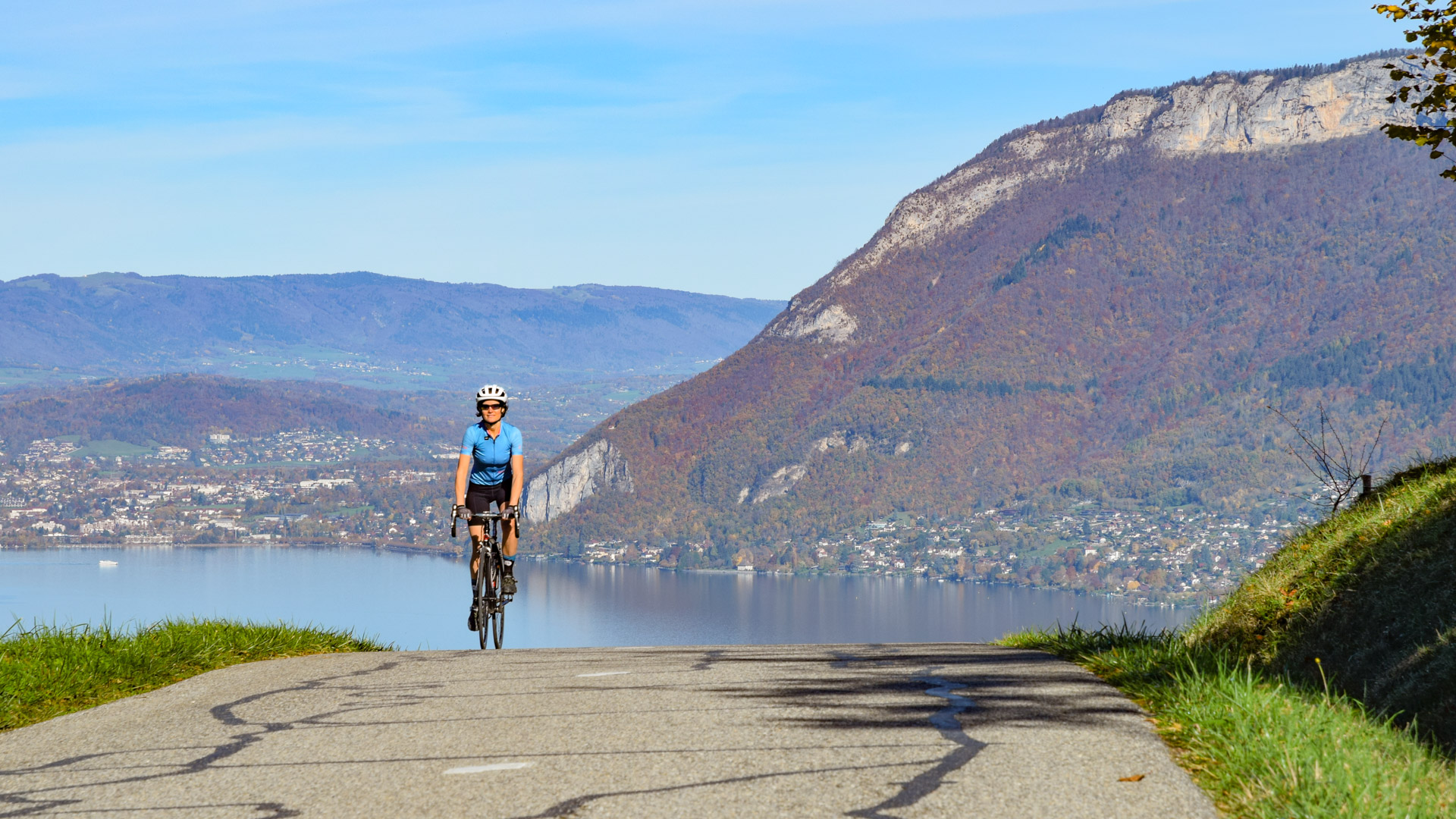cycliste grimpe une petite route qui surplombe le lac d'Annecy