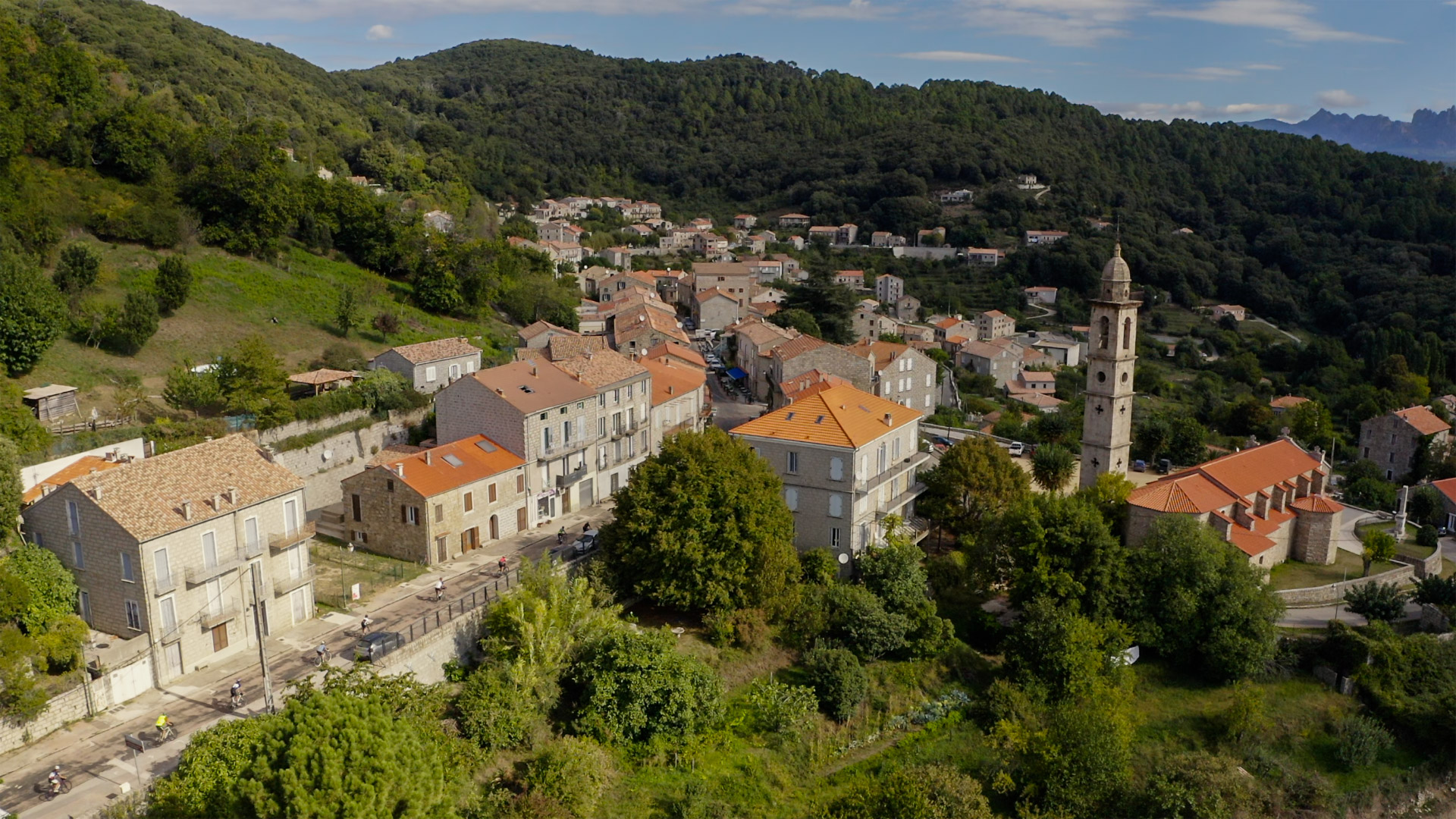 groupe de cyclistes qui arrivent dans la rue principale de Levie, un village typique corse