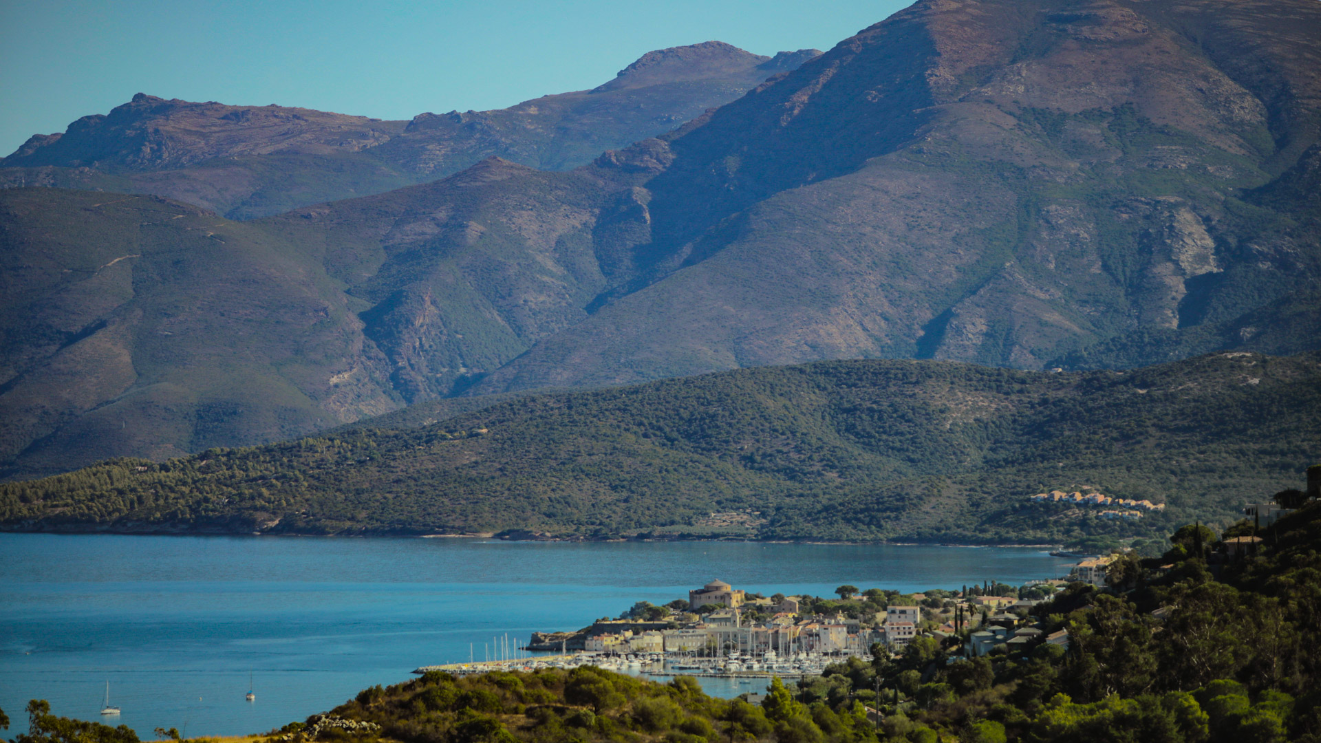 village portuaire corse avec des montagnes en fond