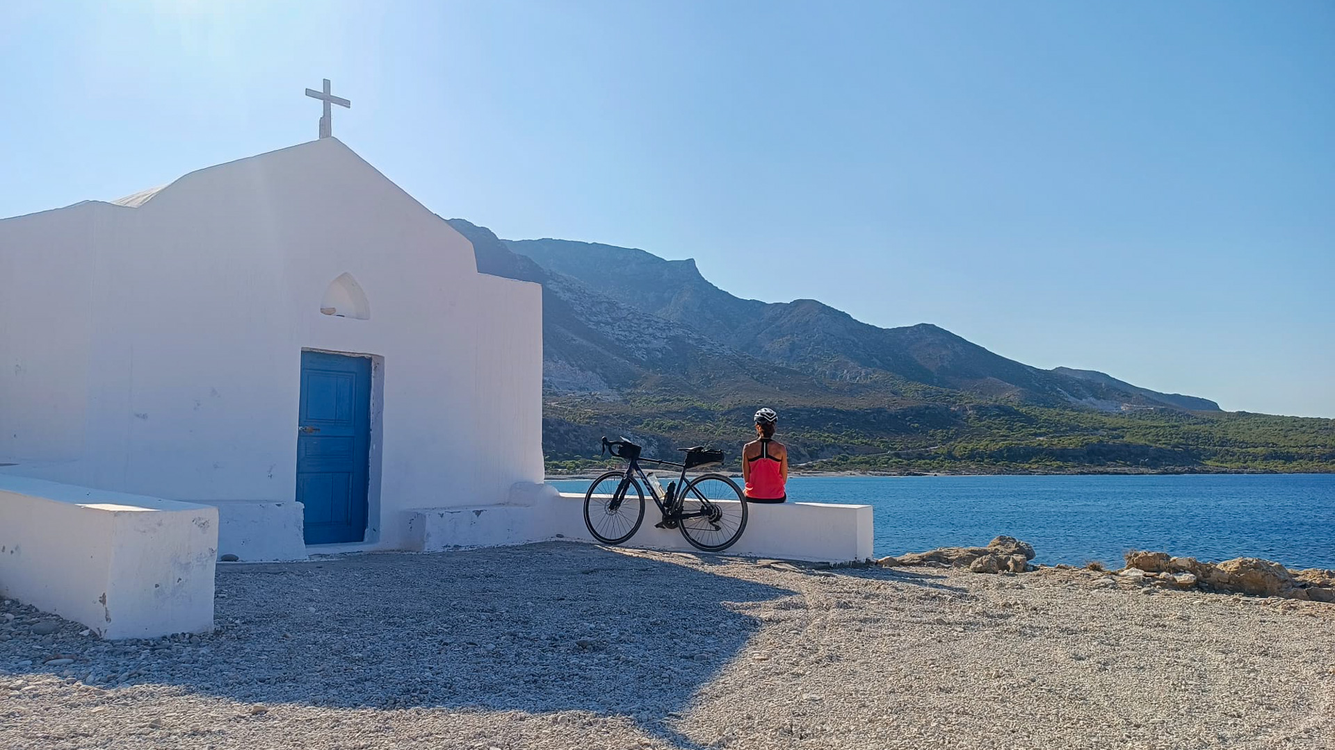 femme assise à coté d'une chapelle avec son vélo au bord de la mer méditerranée