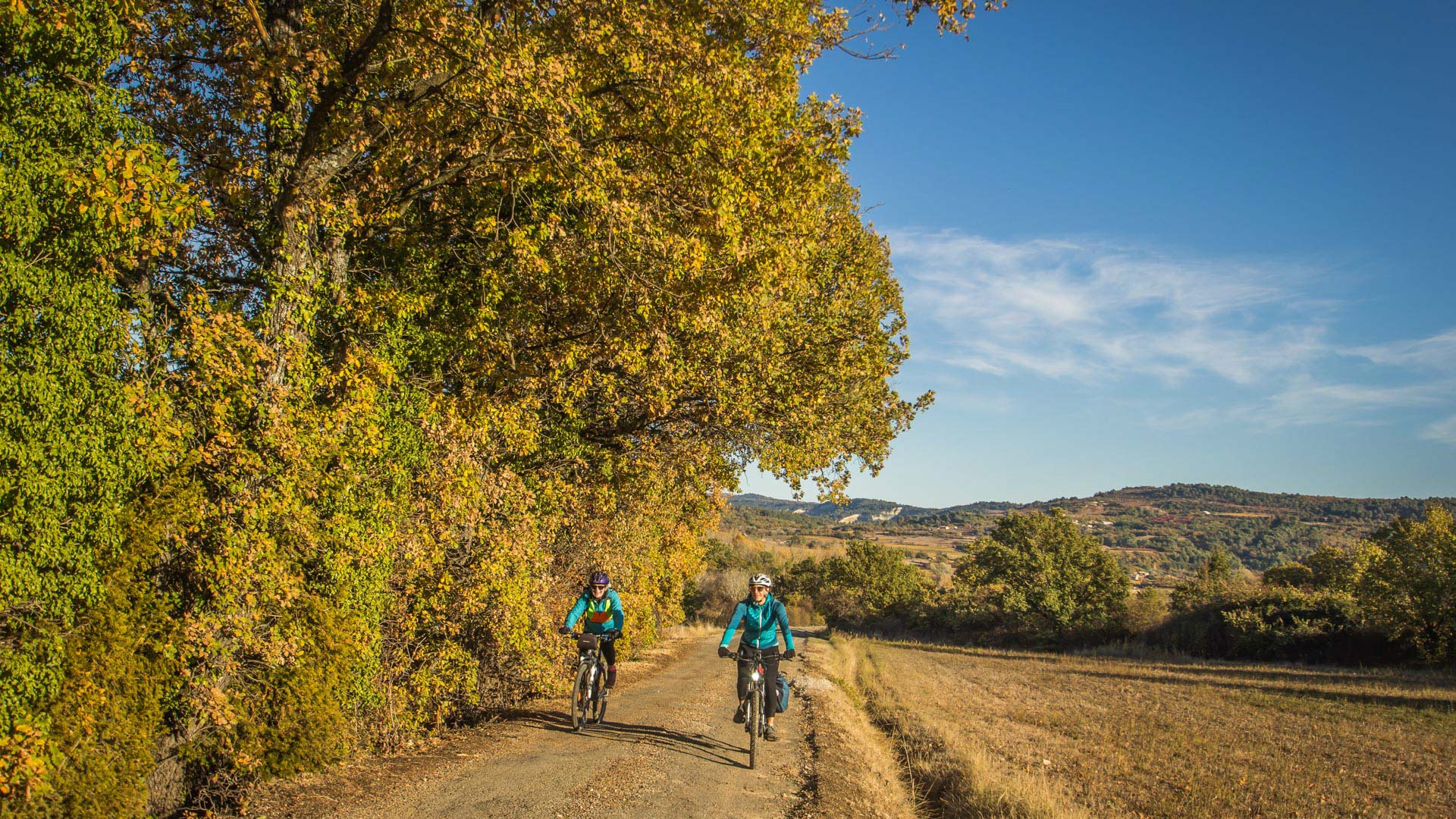 deux femmes à vélo sur une petite route du Luberon en automne
