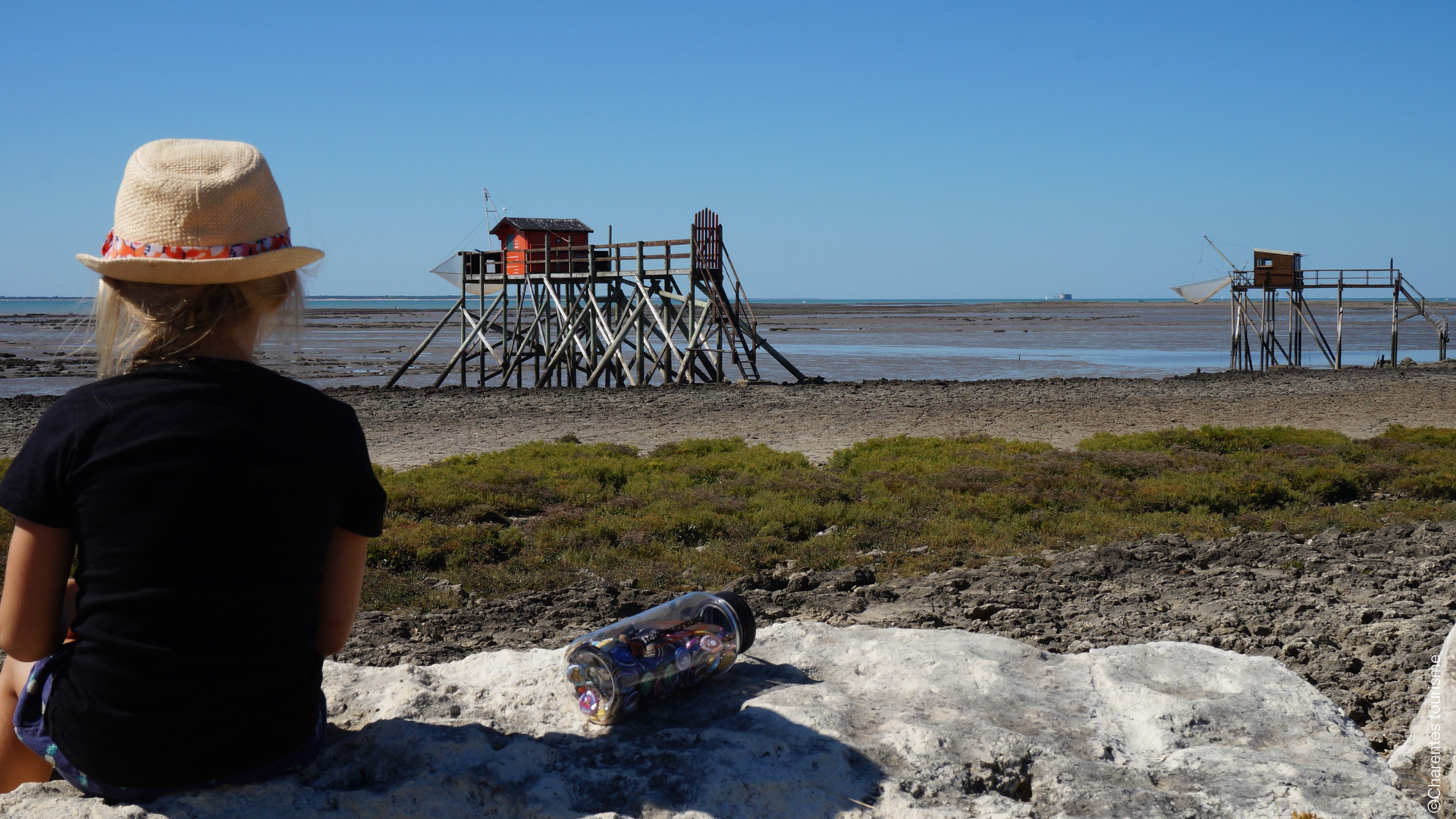 une enfant assise sur la plage contemple l'océan atlantique